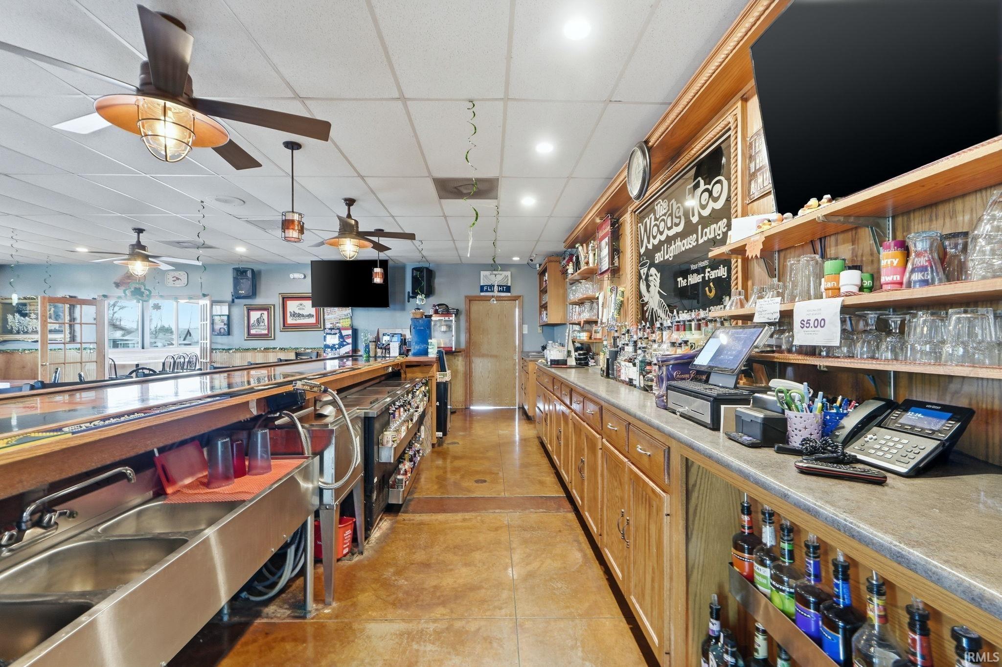 Bar area with light countertops, a paneled ceiling, wood finish cabinets, recessed lighting, and open shelves