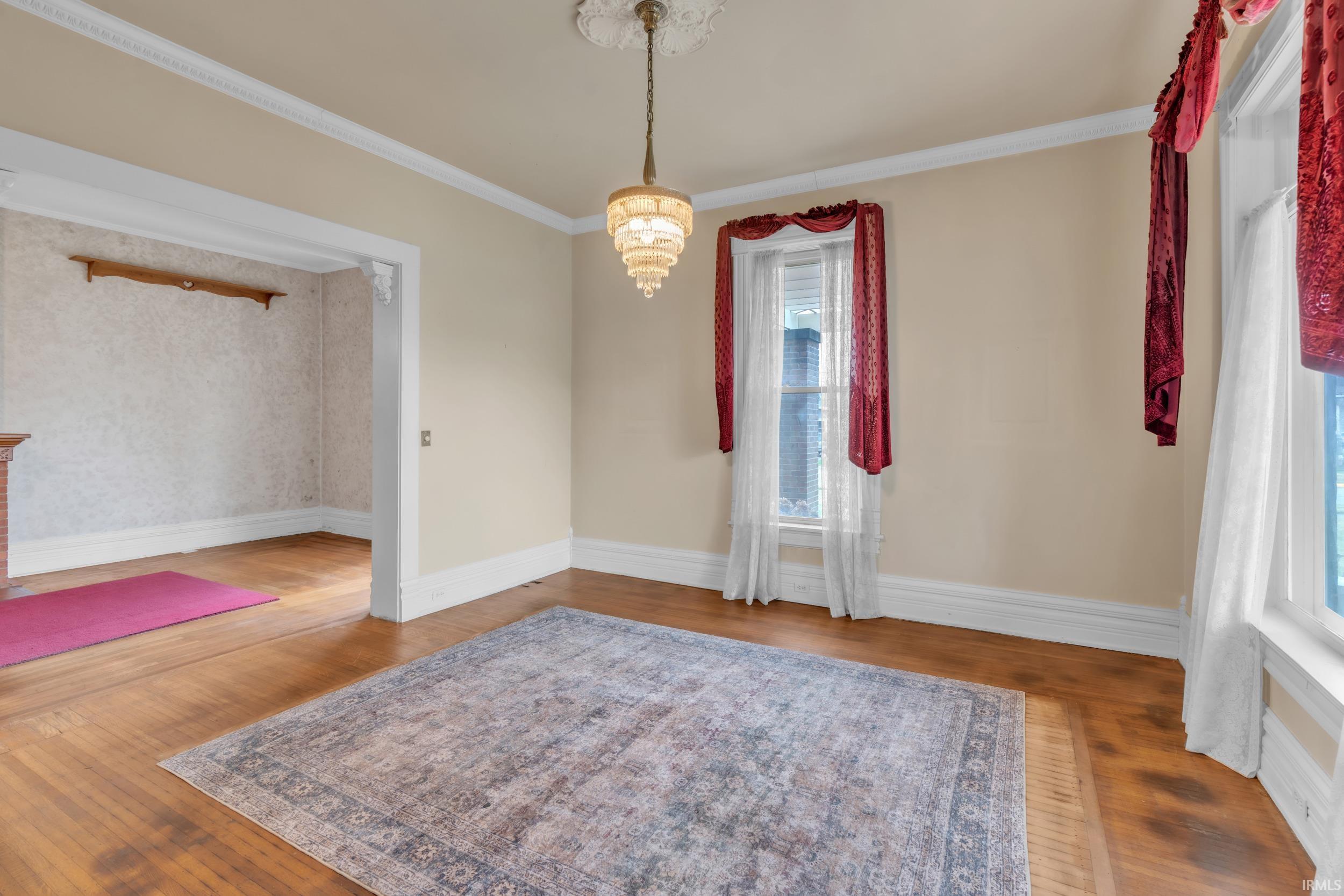 Unfurnished dining area featuring crown molding, hardwood / wood-style floors, and suspended lighting