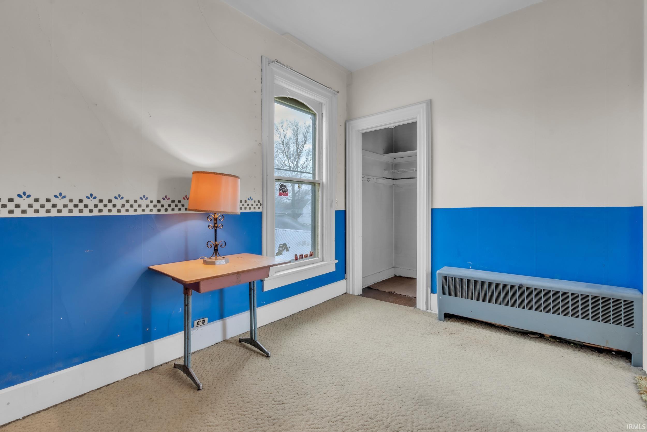 Unfurnished bedroom with radiator heating unit and light carpet