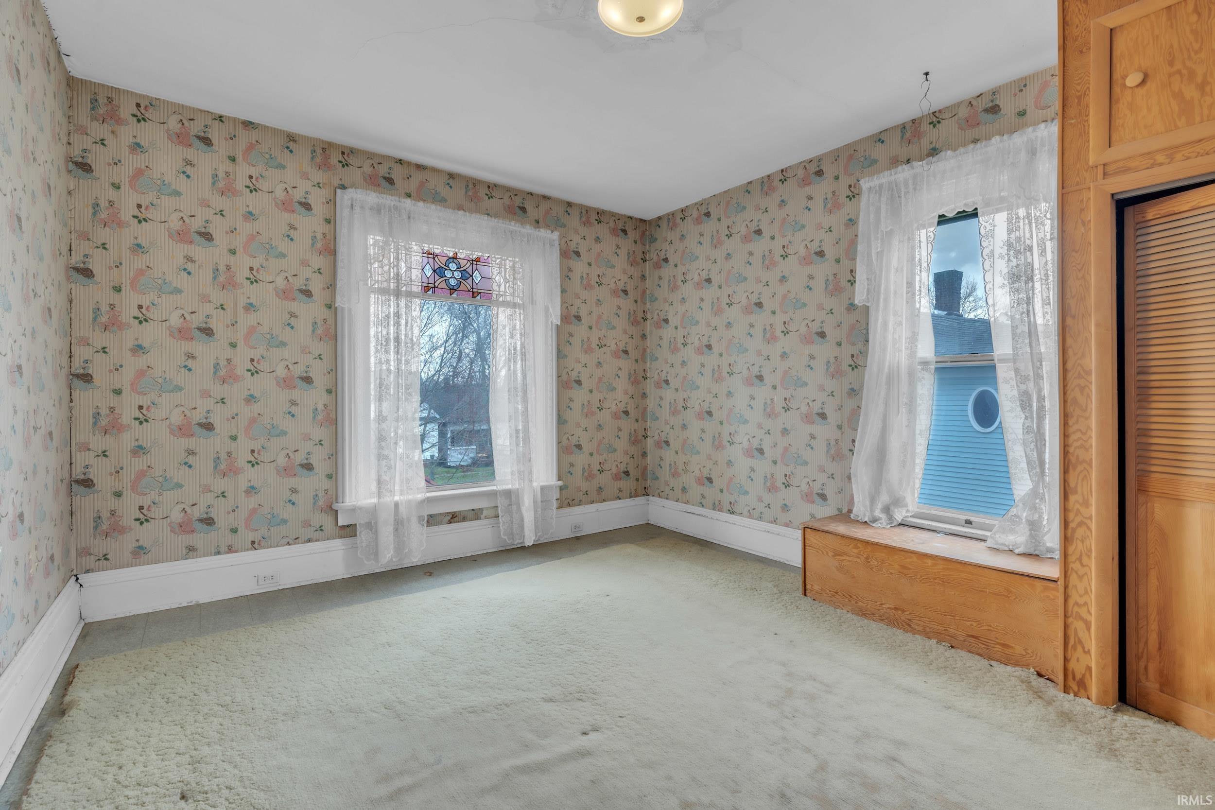 Spare room with wallpapered walls and light carpet