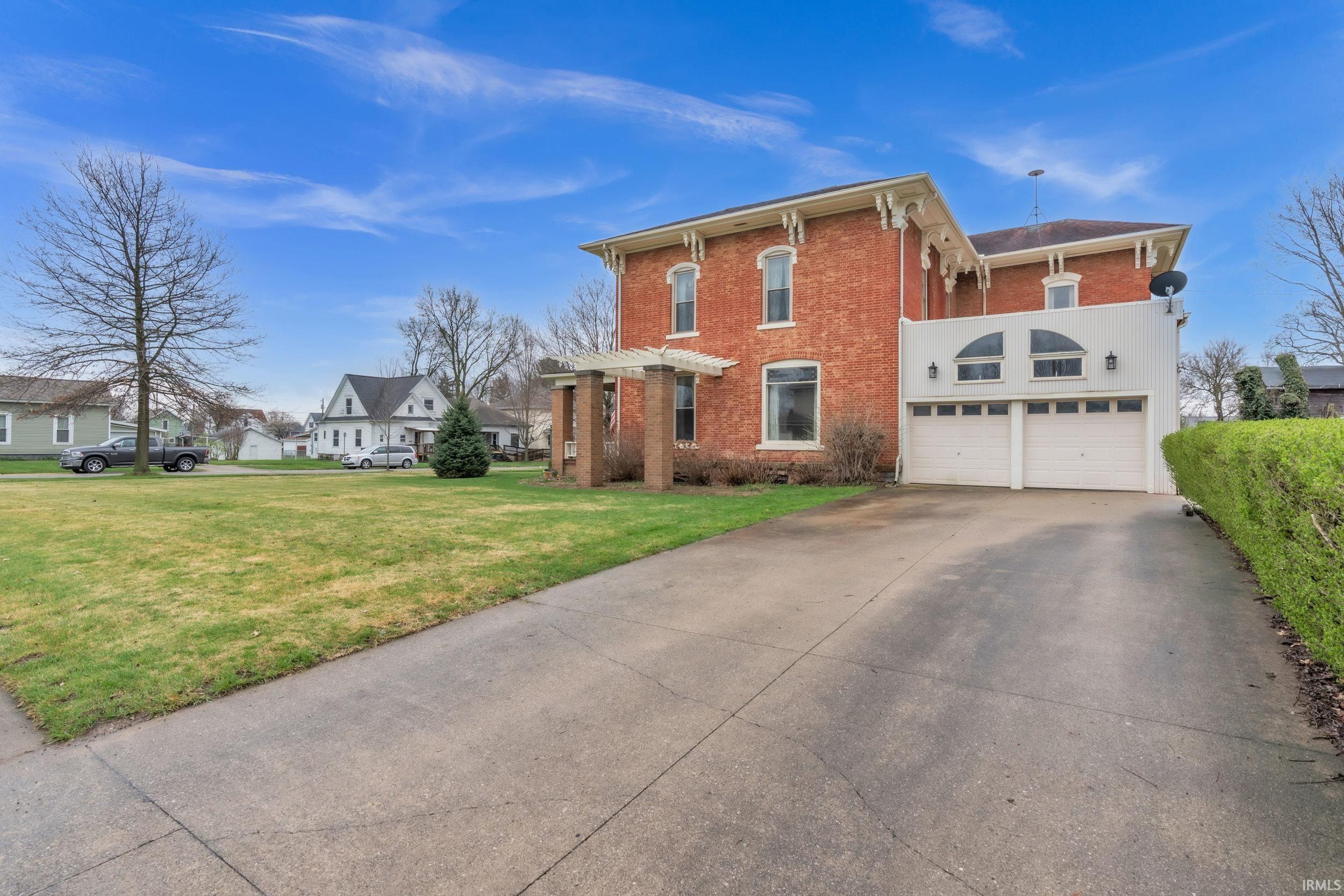 View of front facade featuring concrete driveway, brick siding, a front yard, and a garage