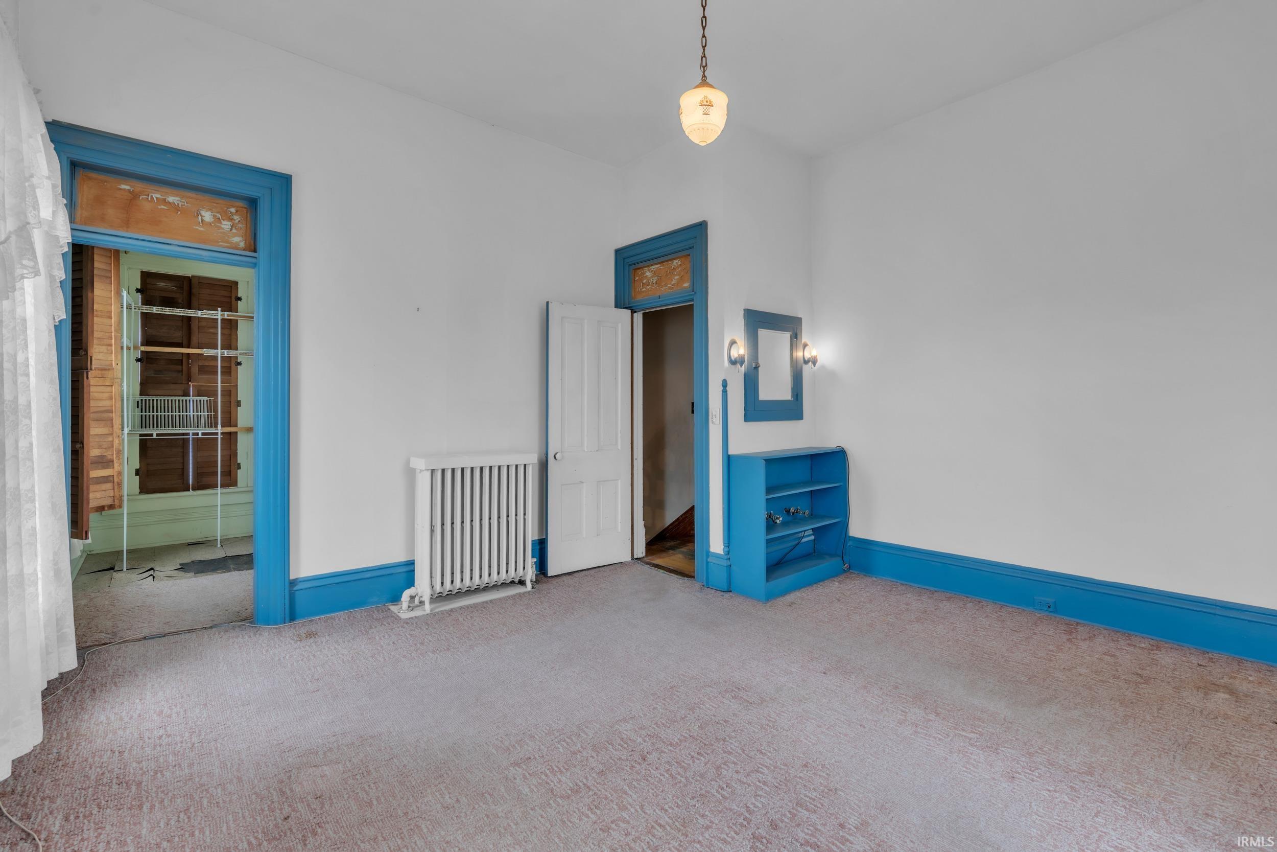 Empty room with radiator, carpet, and electric panel