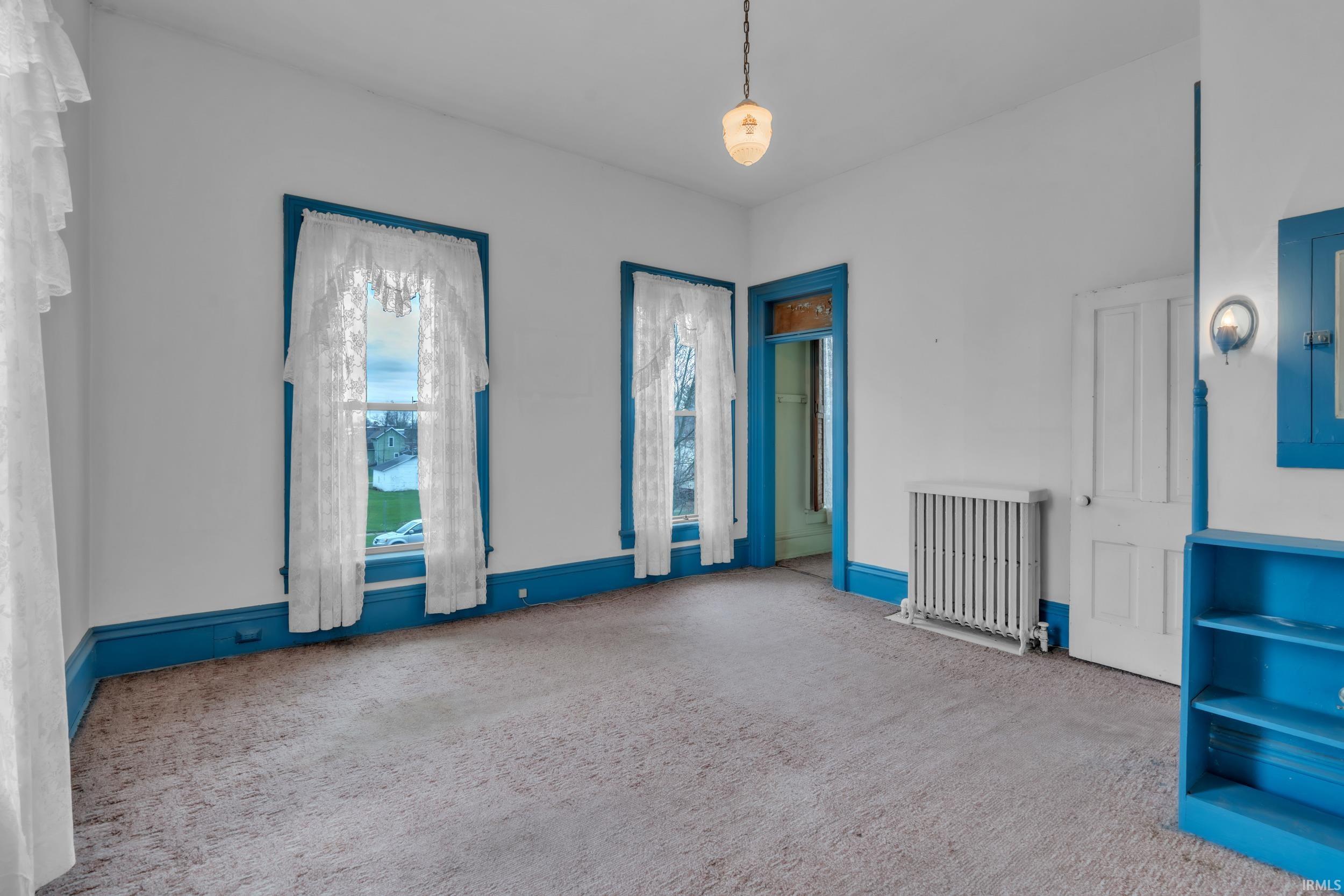 Carpeted empty room with radiator and electric panel