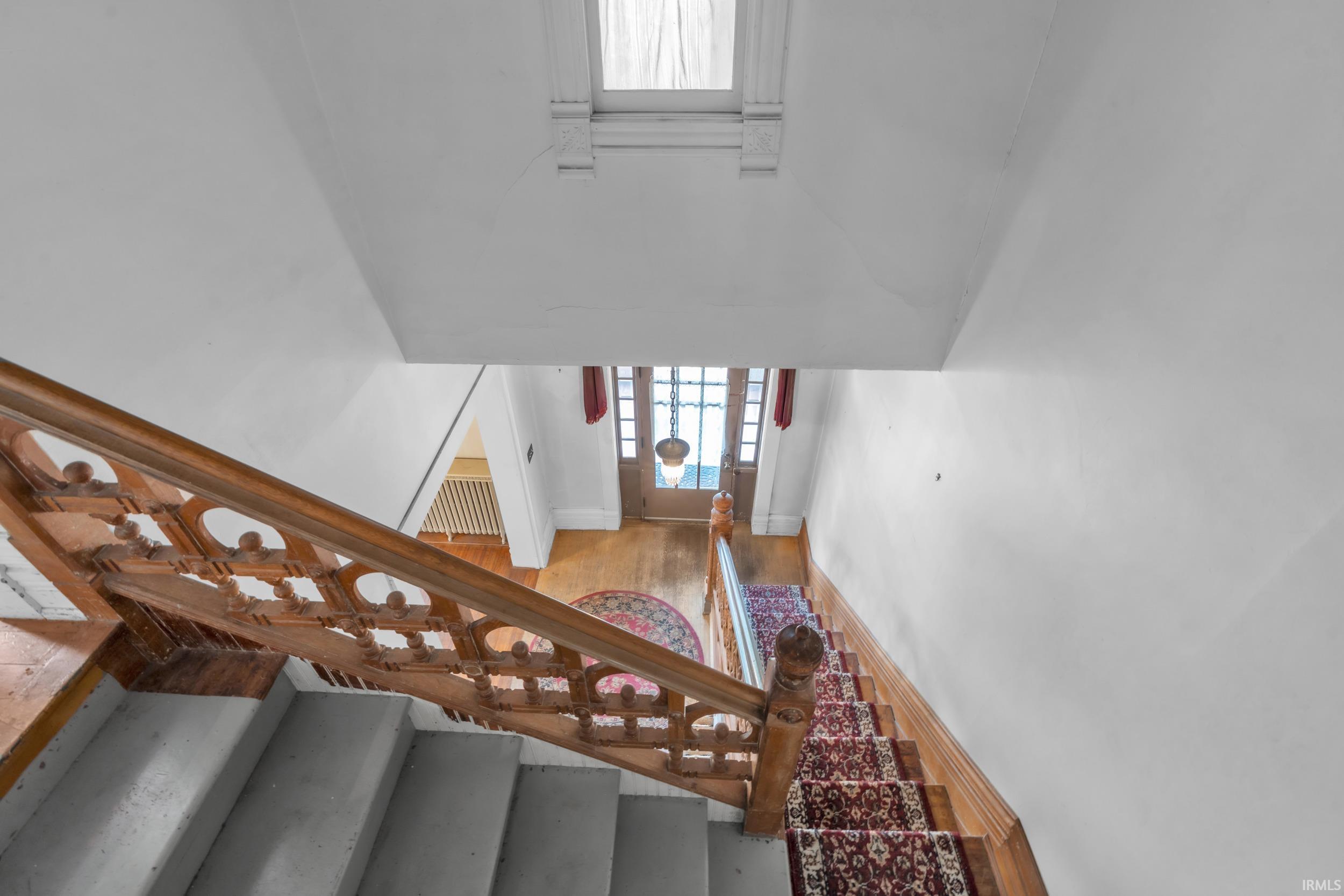 Stairs with wood finished floors and a high ceiling