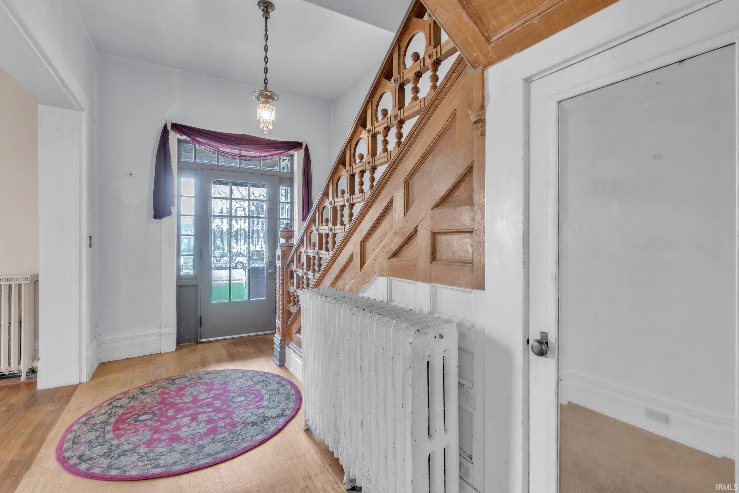 Entrance foyer with radiator heating unit and light wood-style flooring