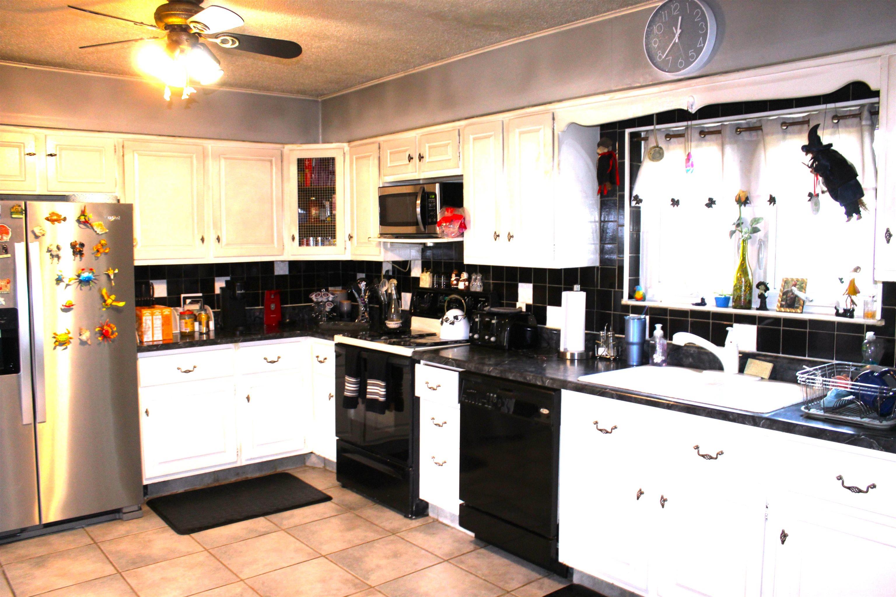 Kitchen with black appliances, backsplash, dark countertops, a textured ceiling, and crown molding