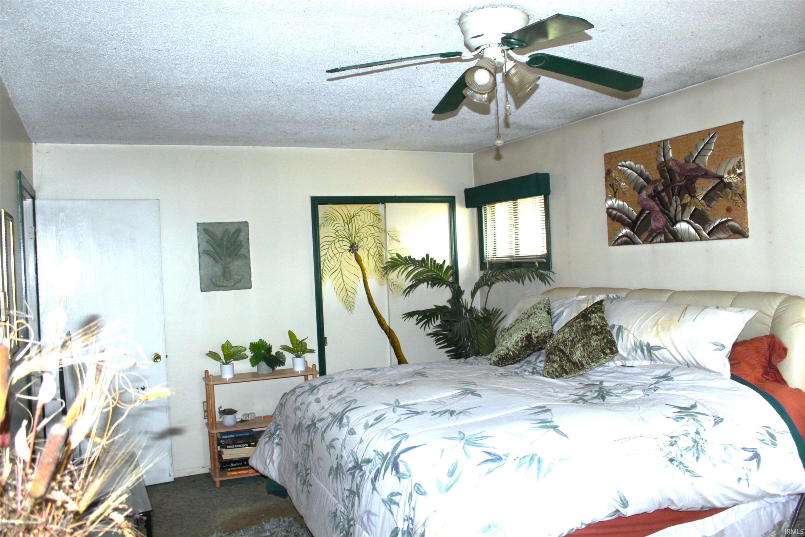 Bedroom with a textured ceiling, a ceiling fan, and dark colored carpet