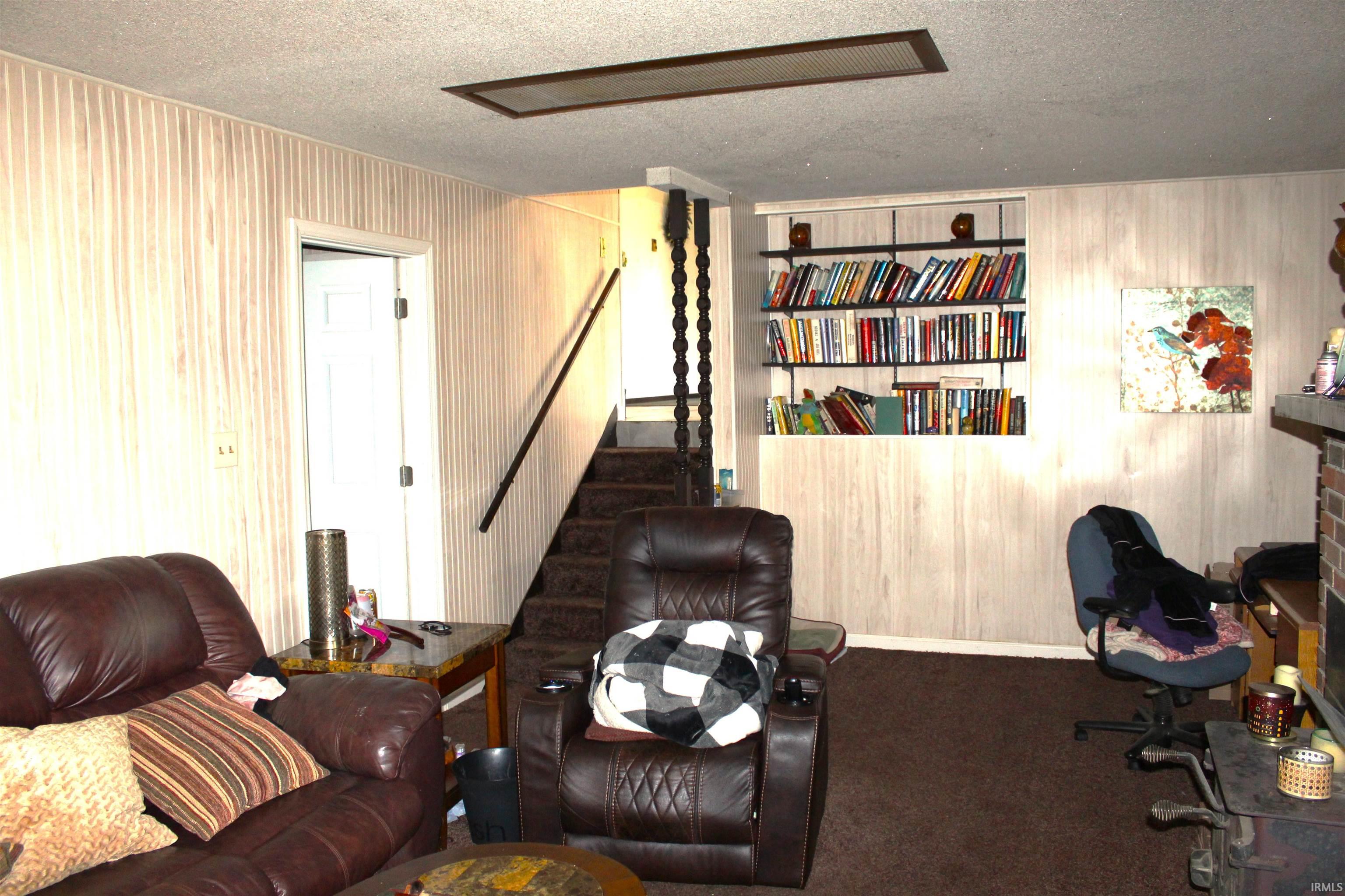 Home office with a textured ceiling, wood walls, and carpet flooring