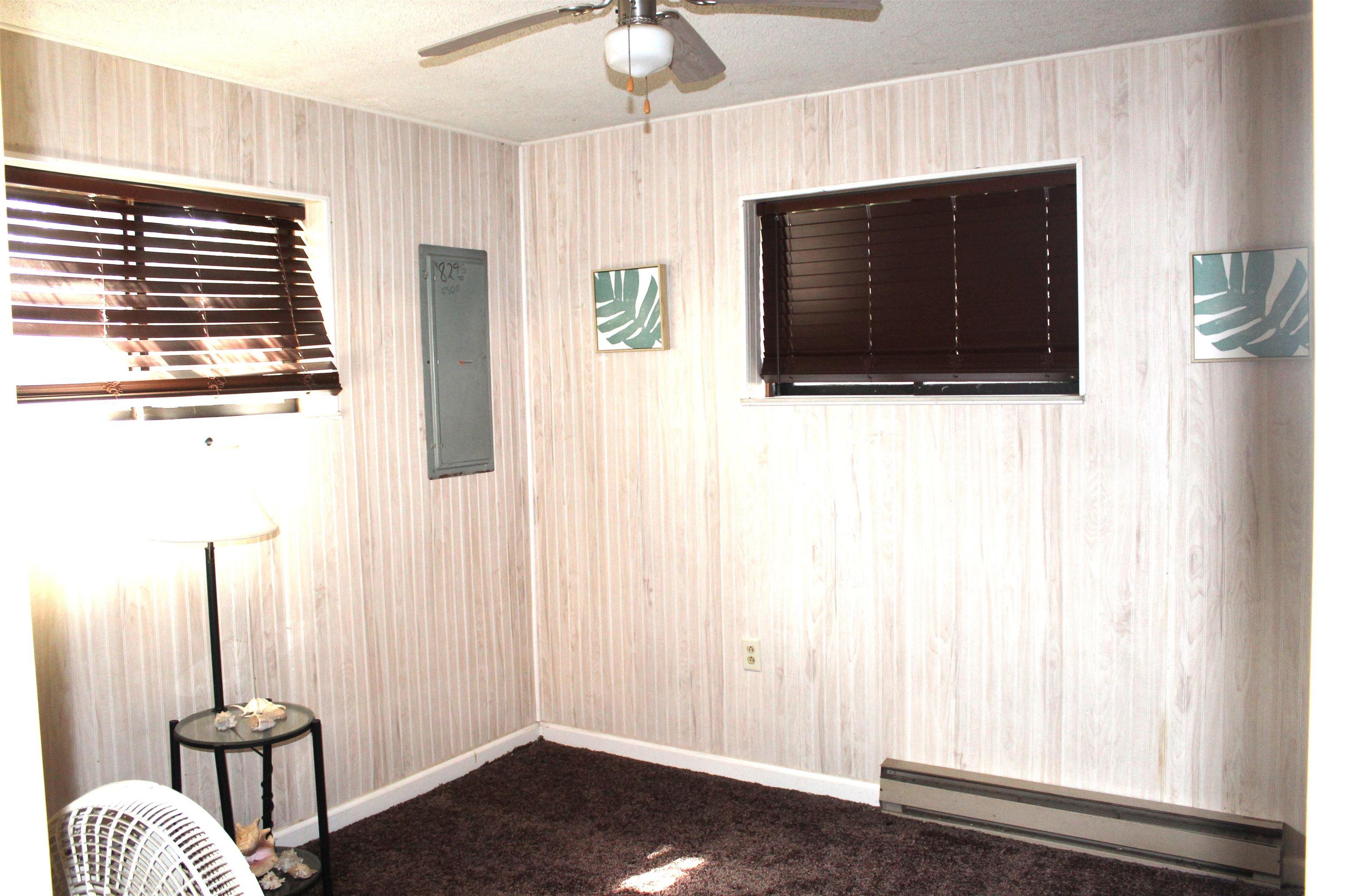 Empty room featuring a baseboard heating unit, a ceiling fan, electric panel, and a textured ceiling