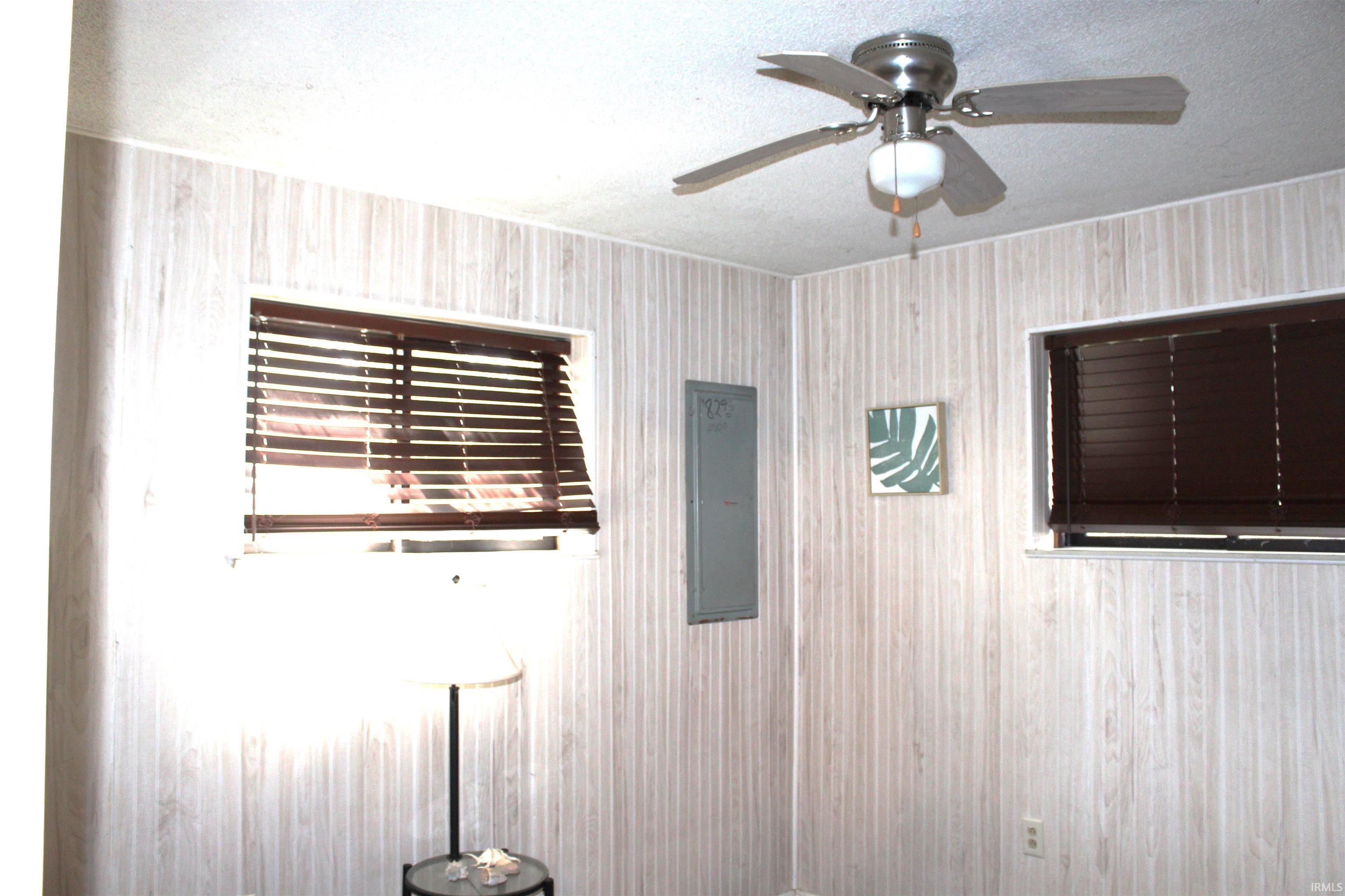 Detailed view of a textured ceiling, electric panel, and a ceiling fan