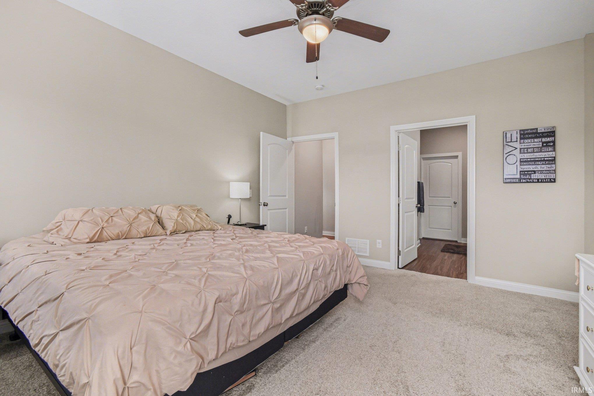 Bedroom featuring carpet, ceiling fan, and ensuite bathroom