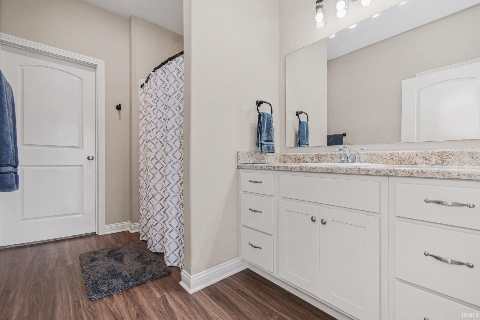 Full bathroom with vanity, a shower with curtain, and dark wood-type flooring