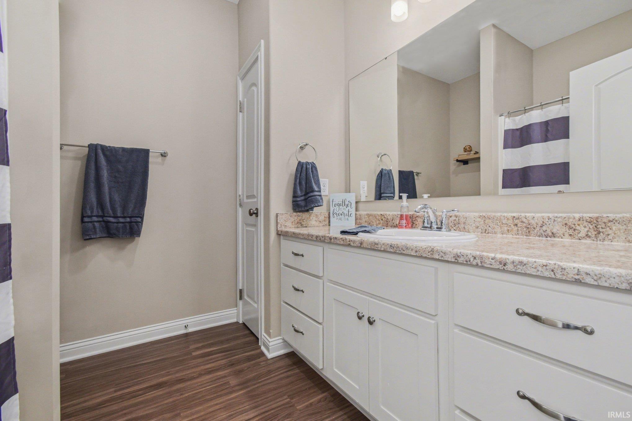 Full bath with vanity, a shower with curtain, and dark wood-type flooring