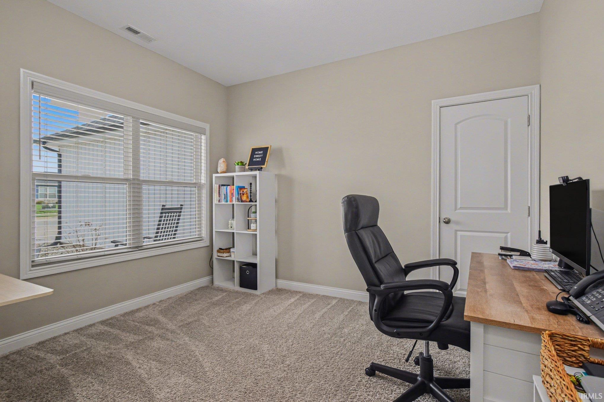 Home office featuring light carpet and baseboards