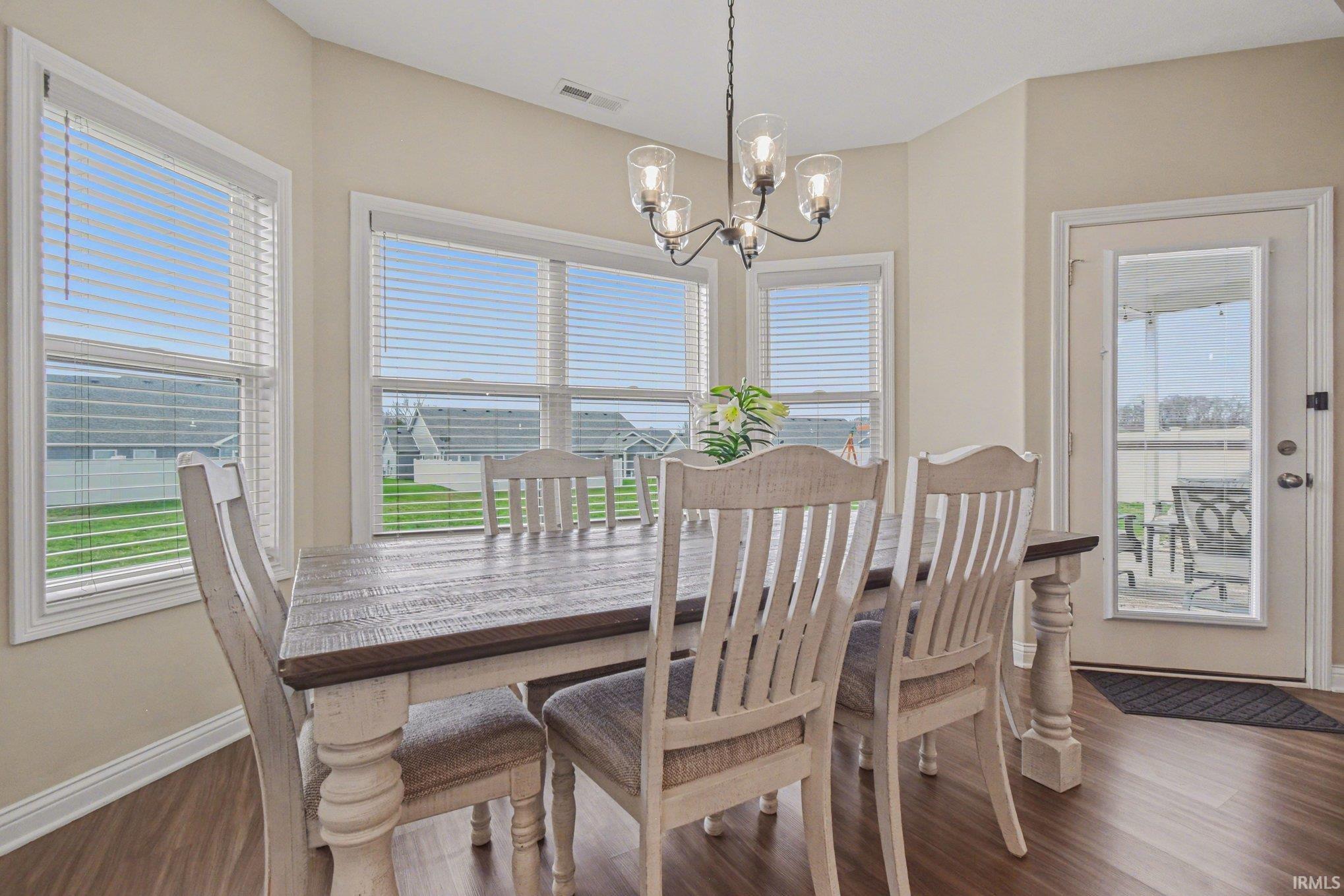 Dining area featuring hanging lights and dark wood-style floors