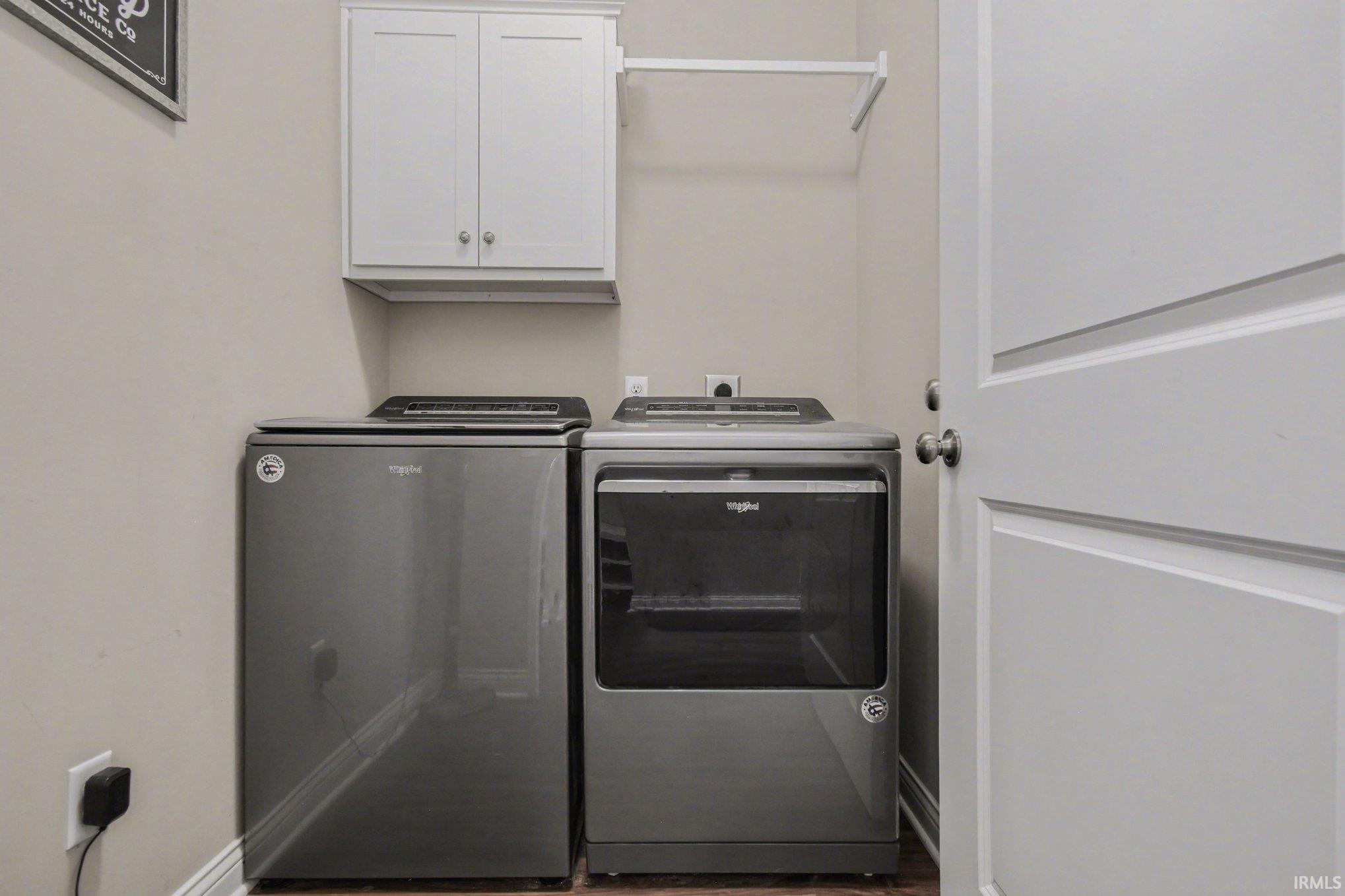 Laundry room with washer and clothes dryer, cabinet space, and wood finished floors