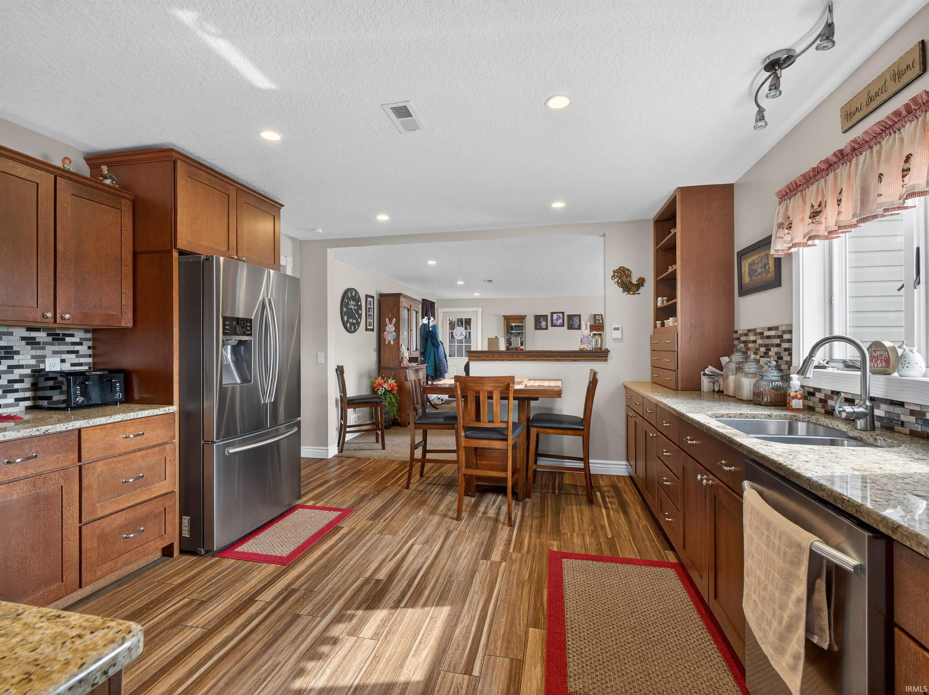 Kitchen featuring decorative backsplash, light stone counters, stainless steel appliances, light wood-style flooring, and recessed lighting