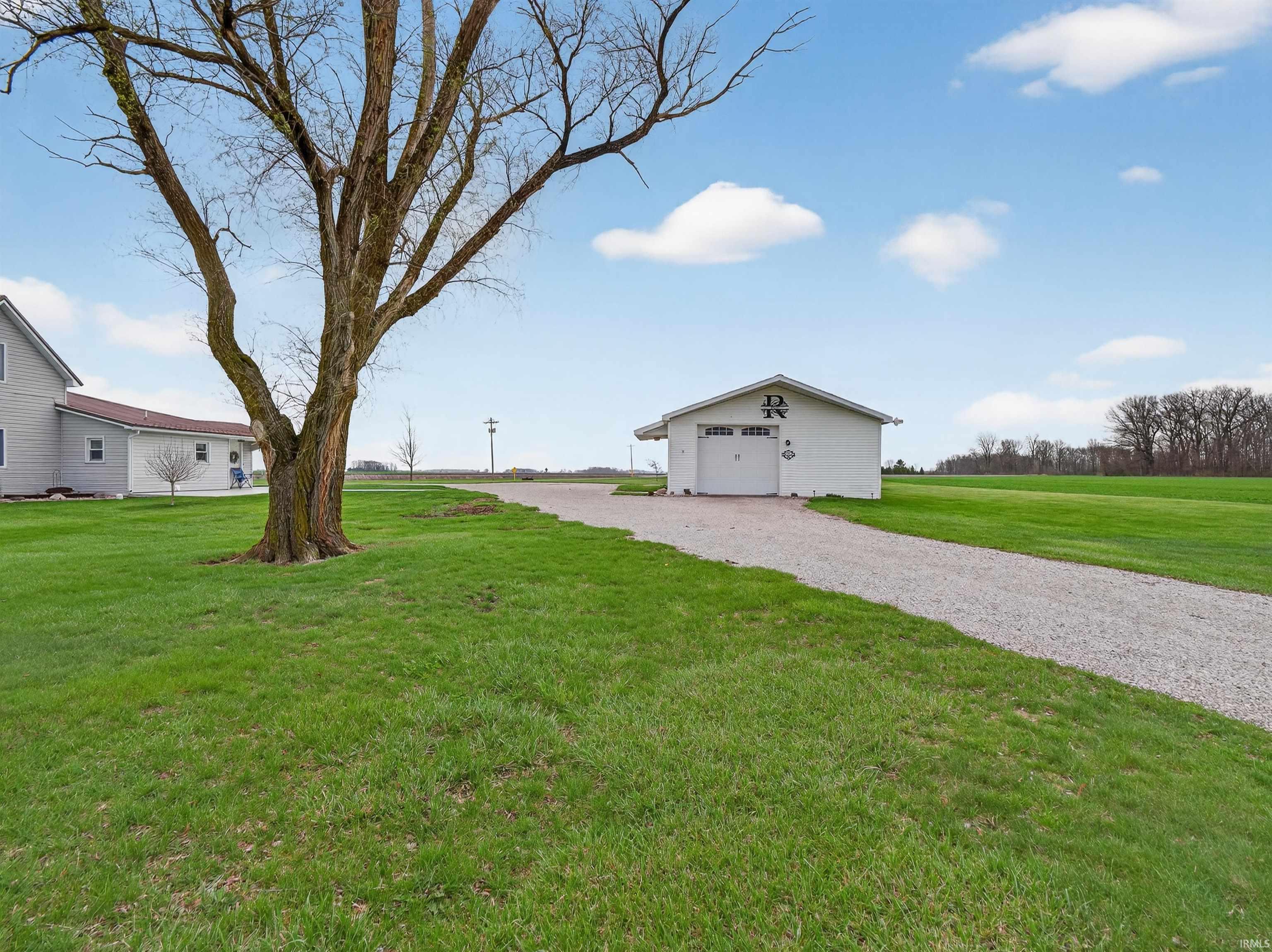 View of grassy yard with an outdoor structure and gravel driveway