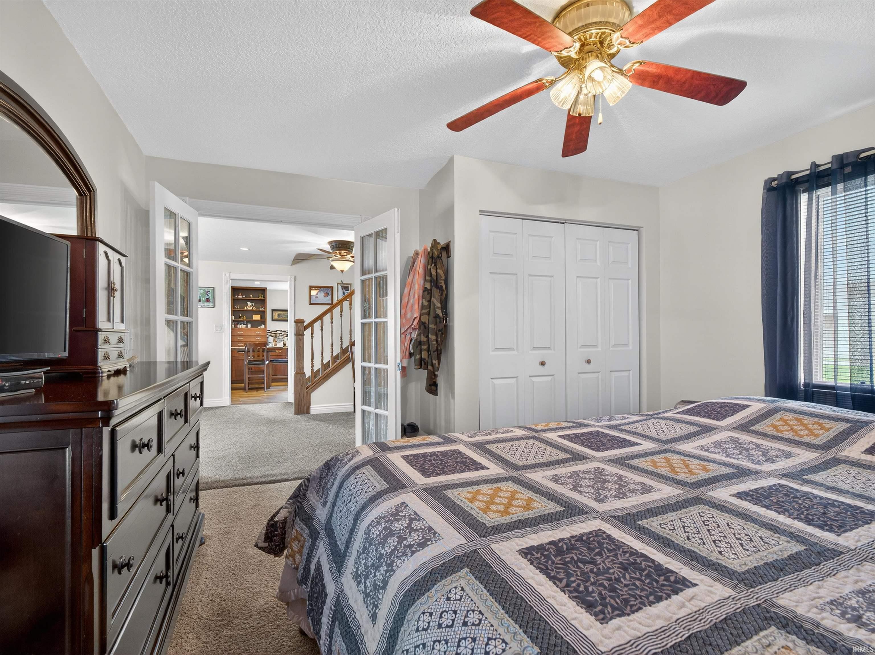 Bedroom featuring light colored carpet, ceiling fan, a textured ceiling, and a closet