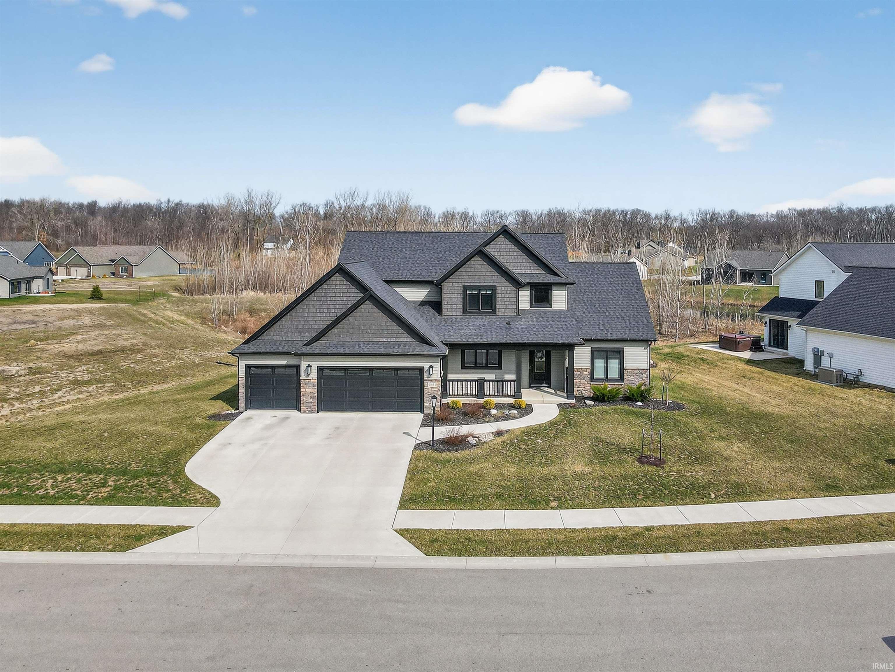 View of front of home with an attached garage, stone siding, driveway, and a front yard