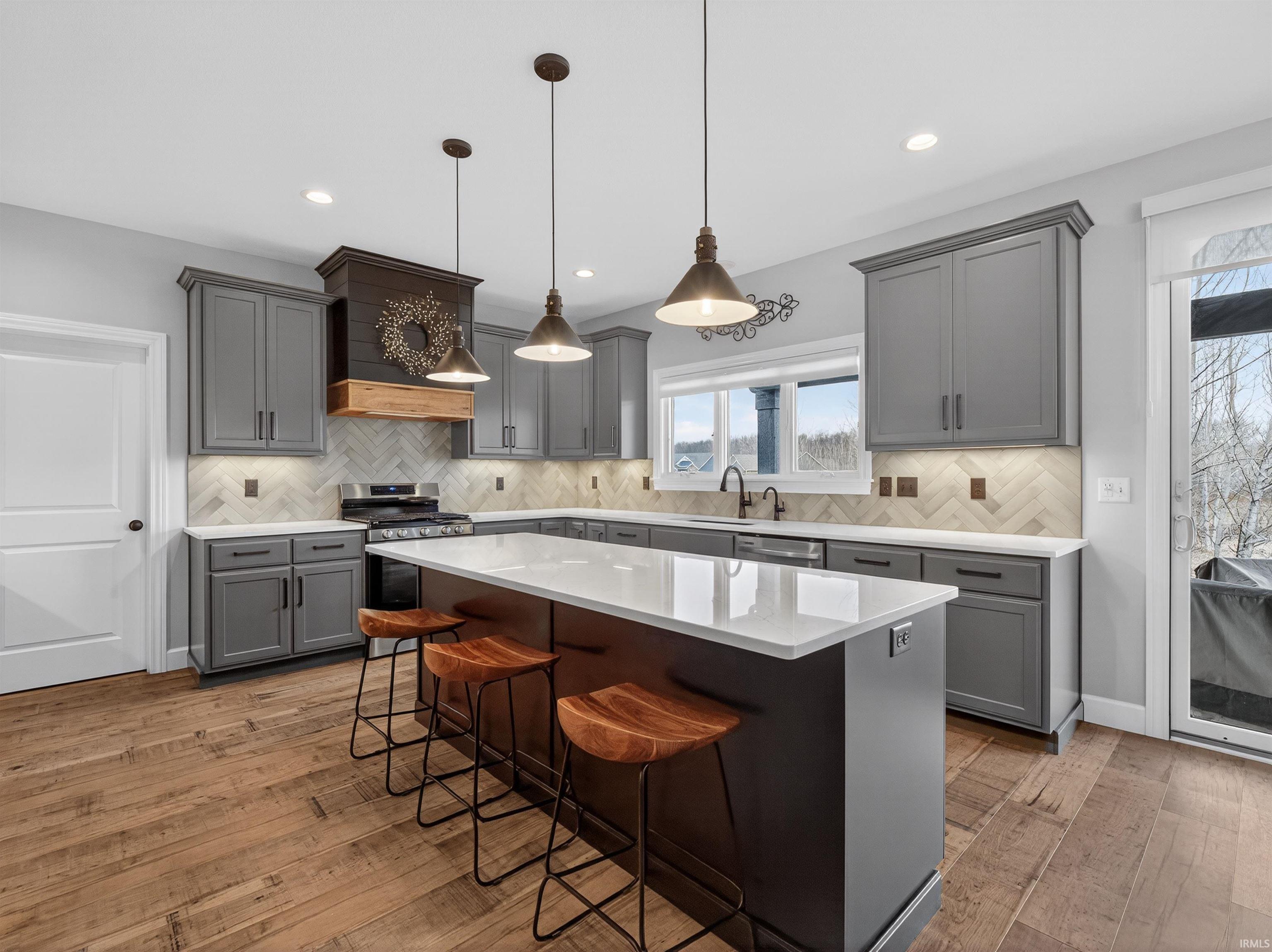Kitchen featuring gray cabinetry, light wood-type flooring, a breakfast bar area, and stainless steel range with gas stovetop