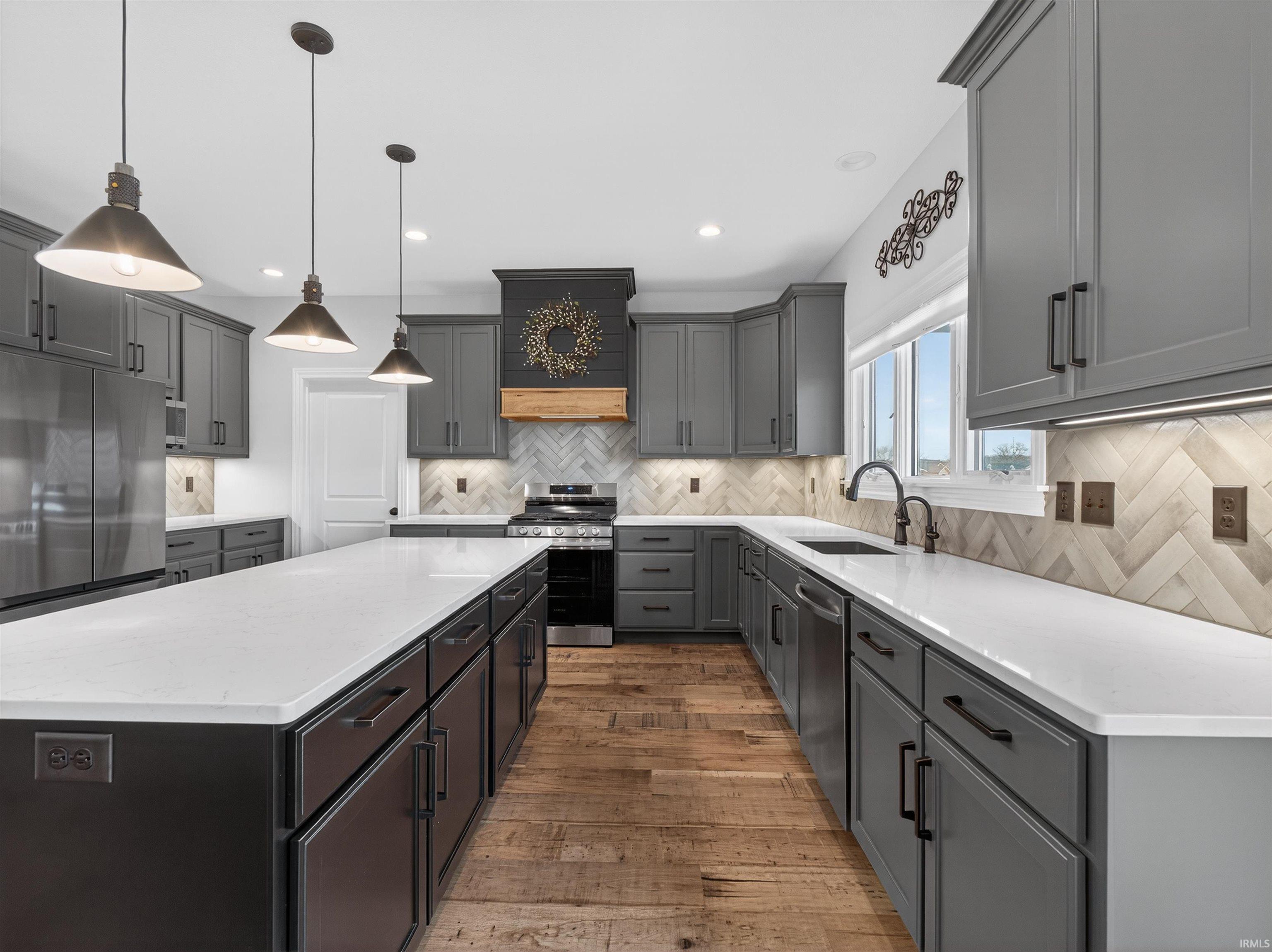 Kitchen featuring gray cabinets, light stone countertops, a kitchen island, and stainless steel appliances