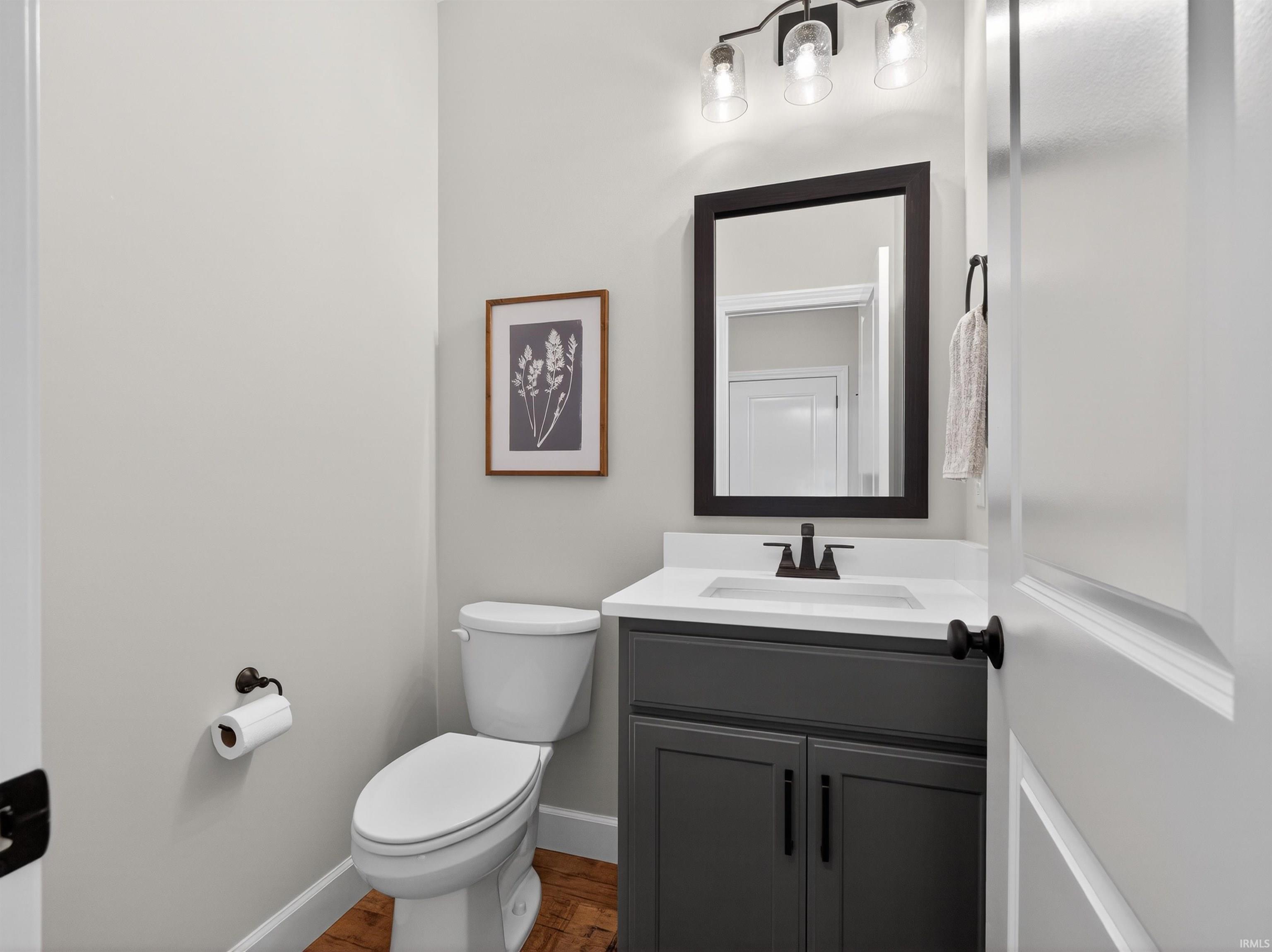Half bath featuring vanity and dark wood finished floors