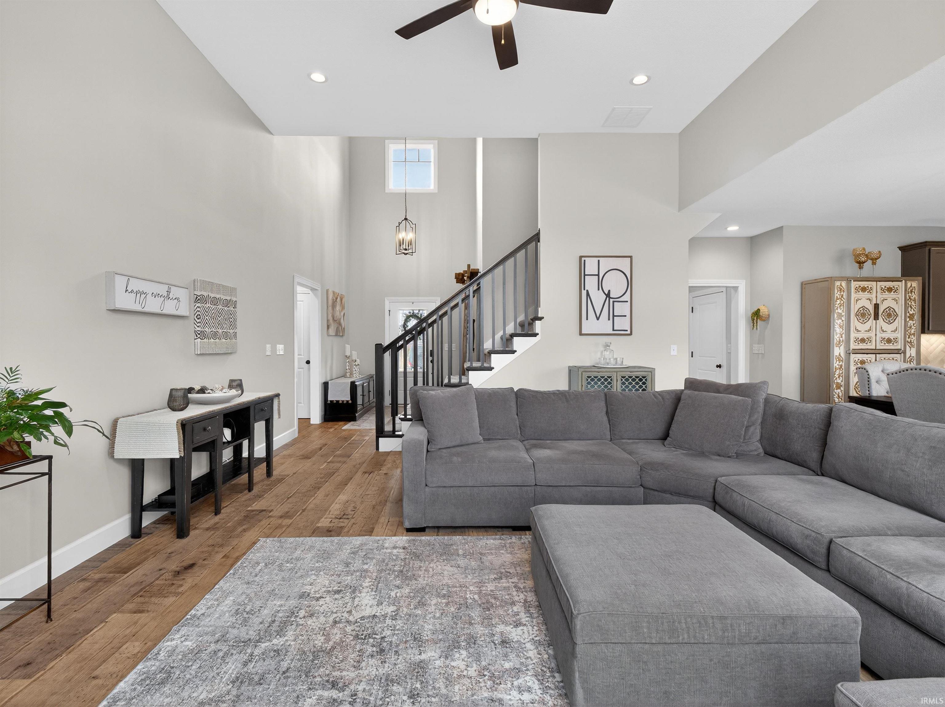 Living area featuring a high ceiling, hardwood / wood-style floors, a ceiling fan, and recessed lighting