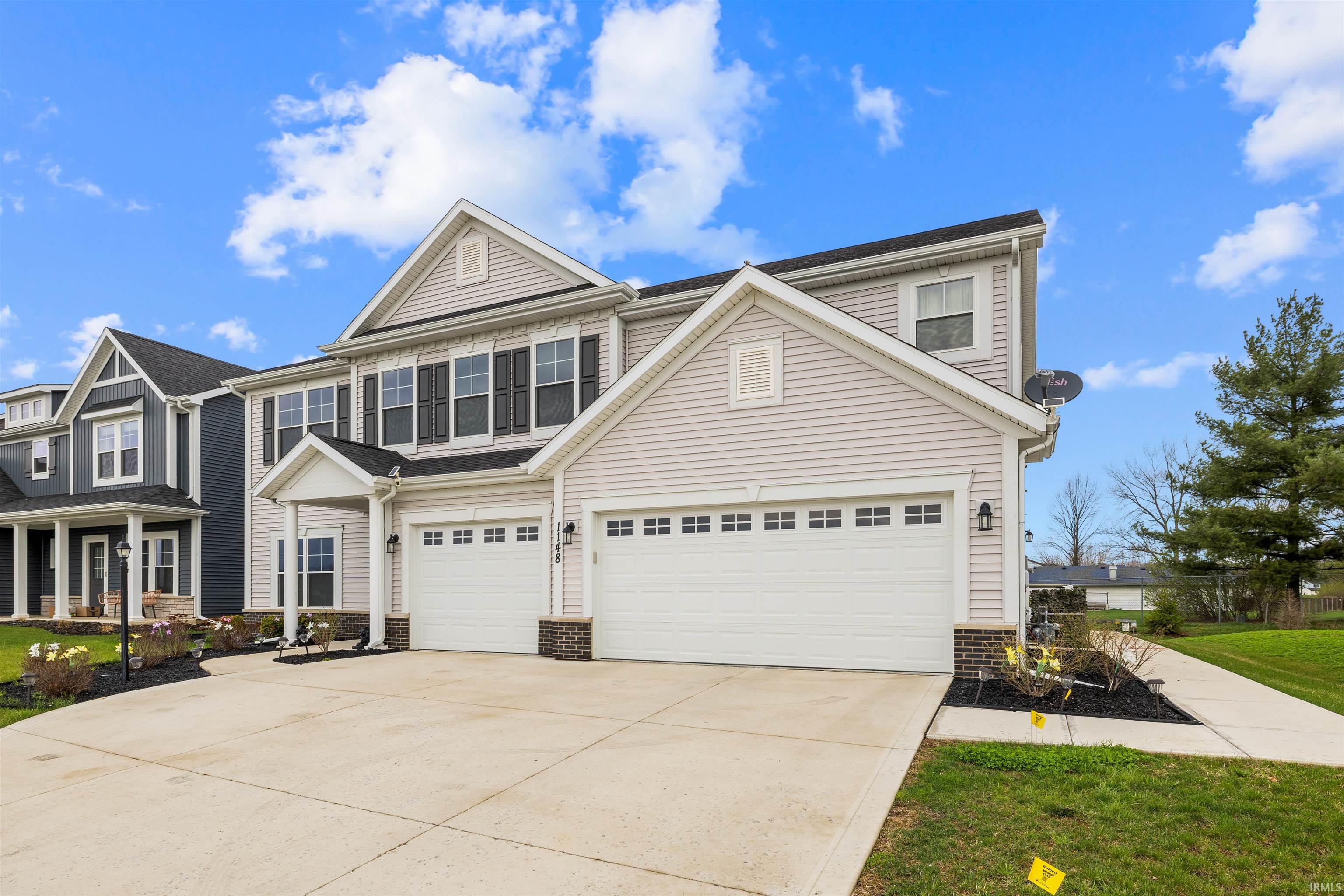 Traditional-style house featuring driveway, brick siding, a garage, and covered porch