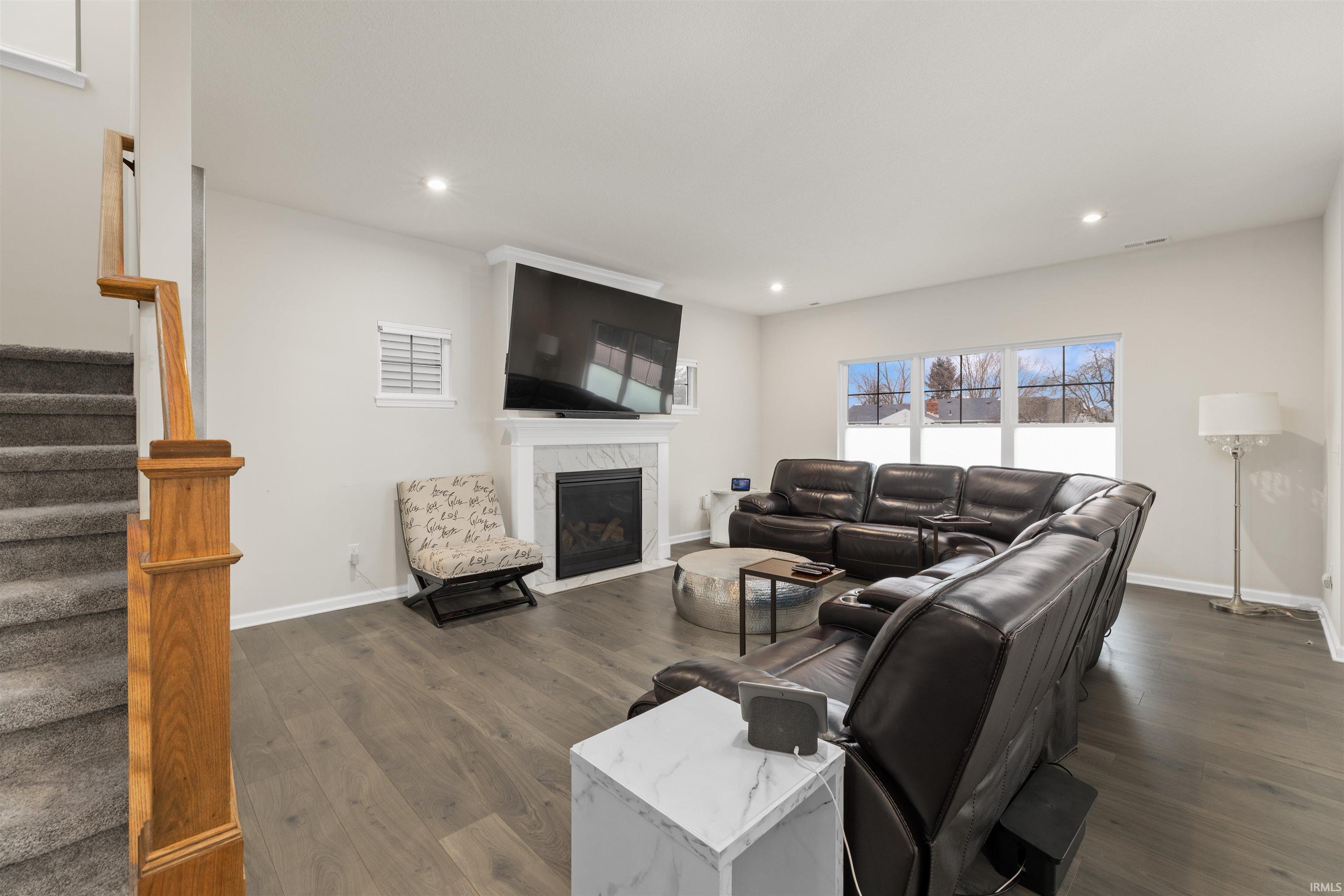 Living room with a fireplace, dark wood-style flooring, and recessed lighting