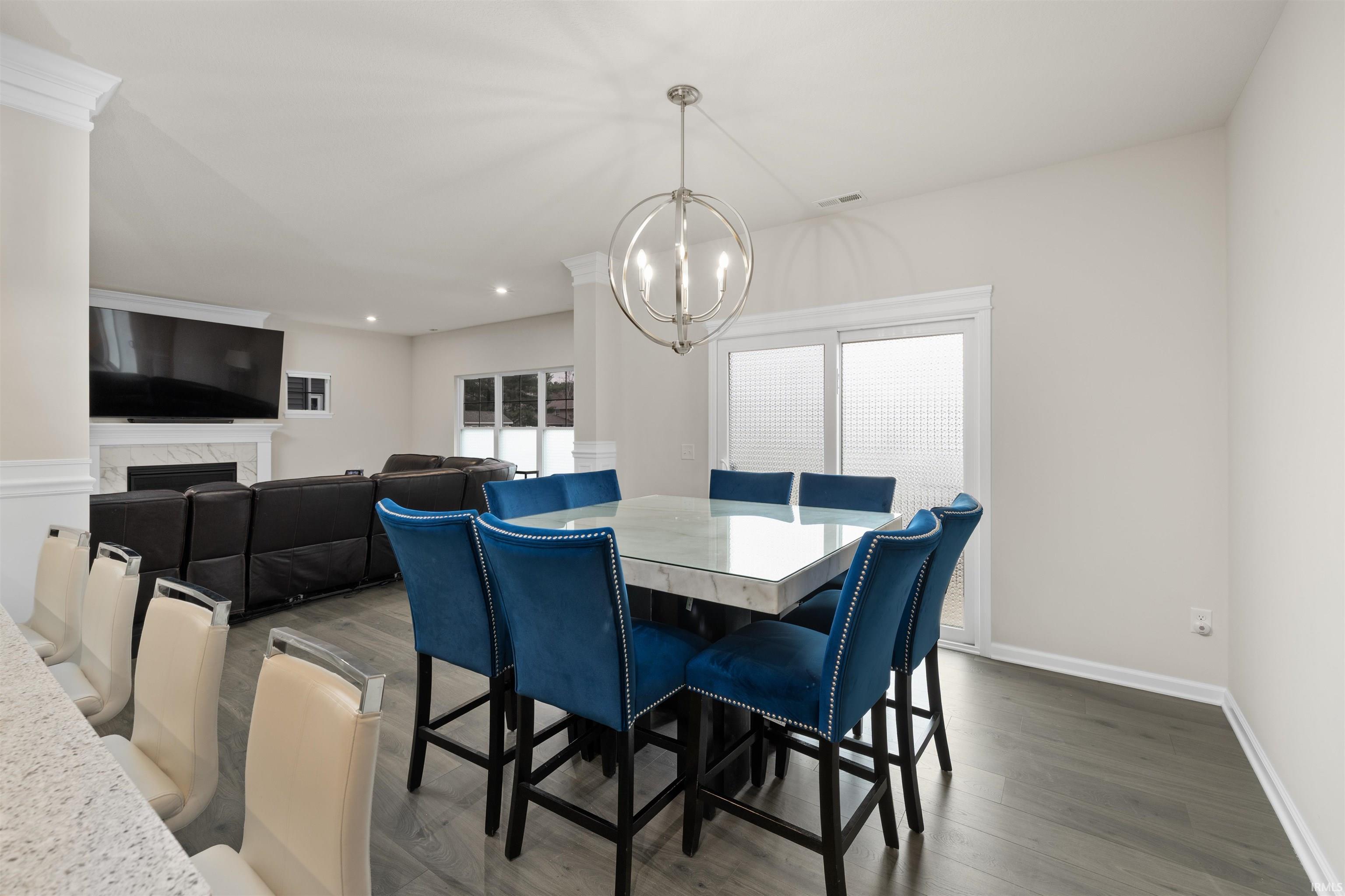 Dining space featuring wood finished floors, hanging lights, and a premium fireplace