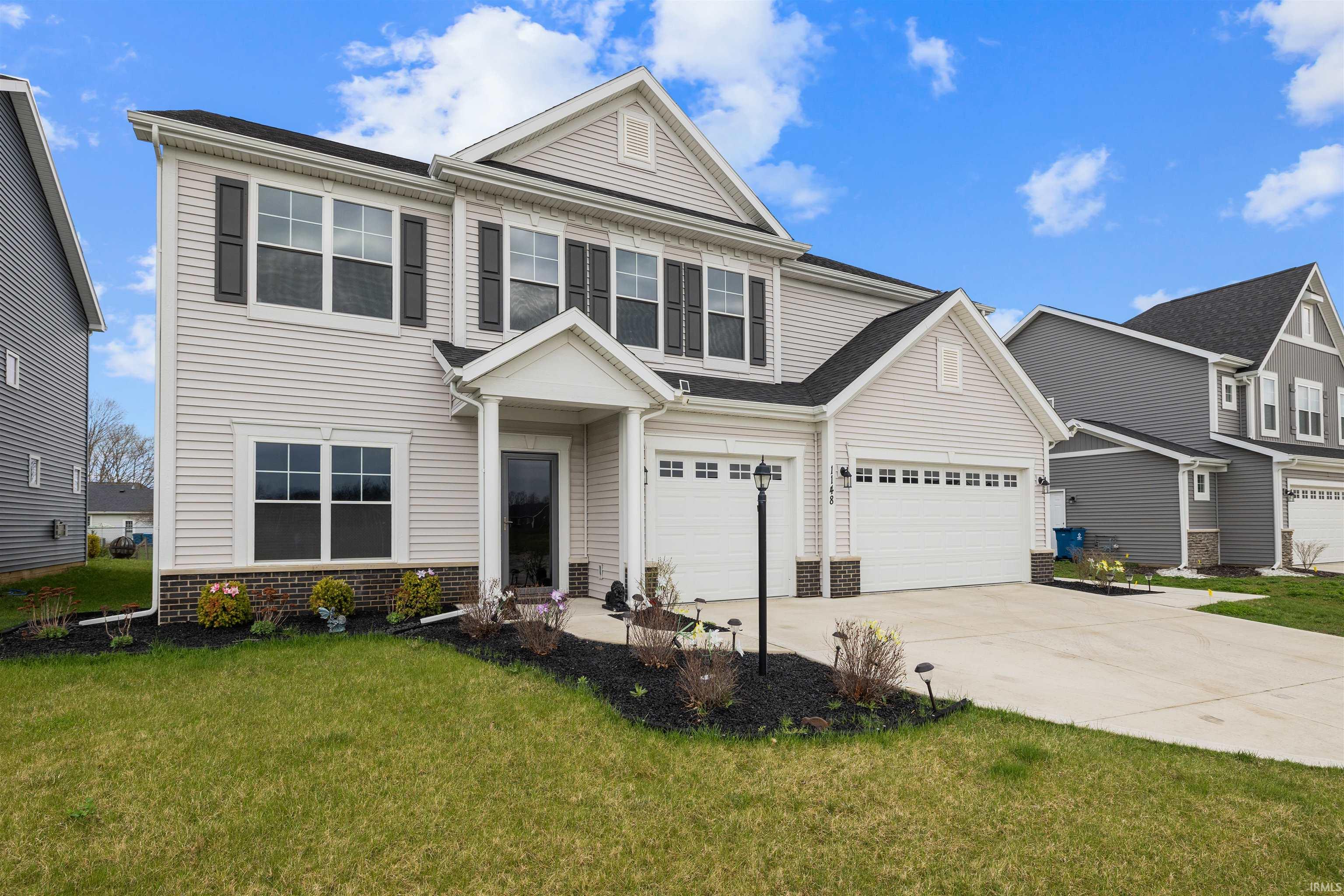Traditional home with concrete driveway, brick siding, a front lawn, and a garage