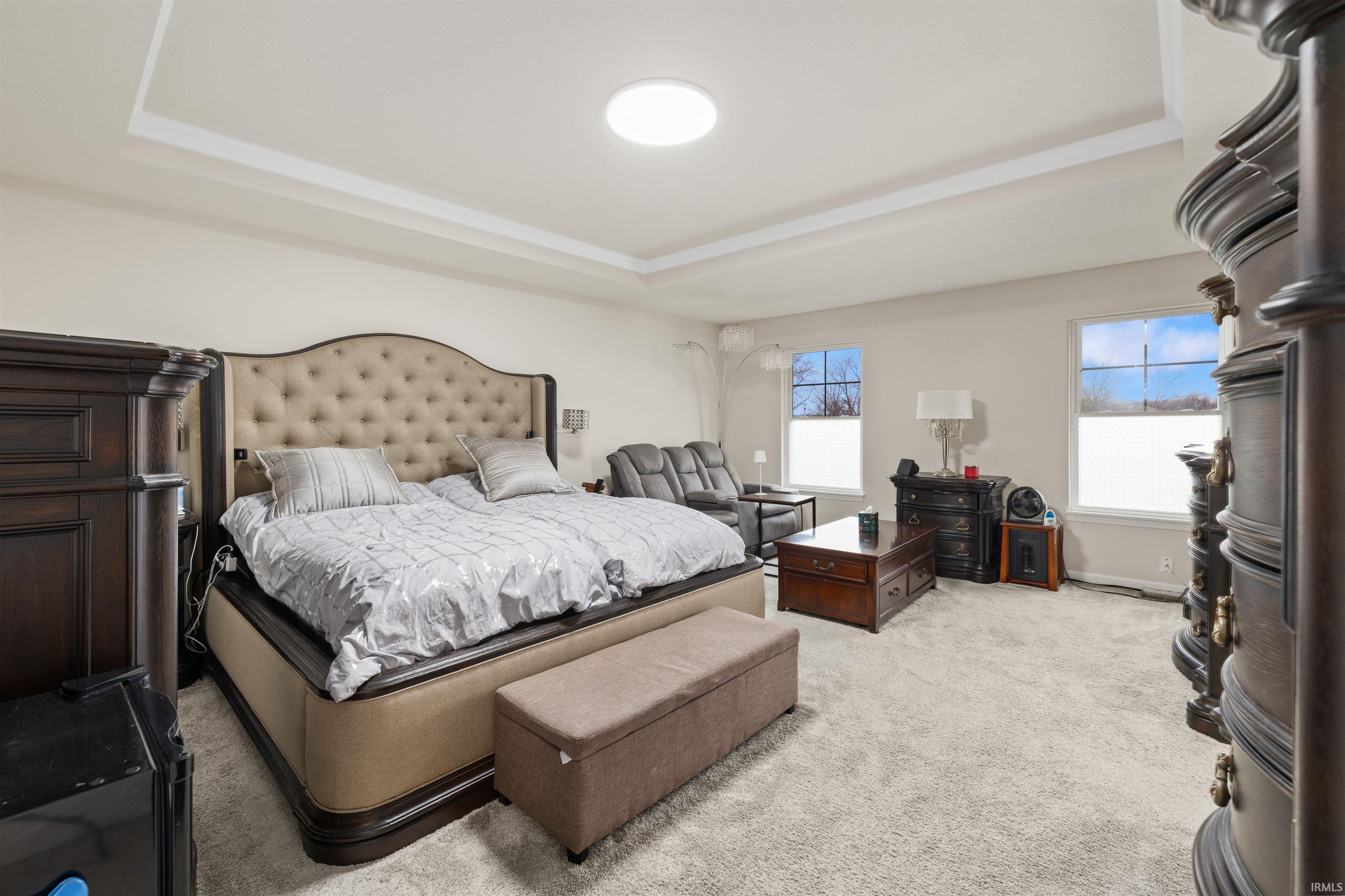 Bedroom with a tray ceiling and light colored carpet