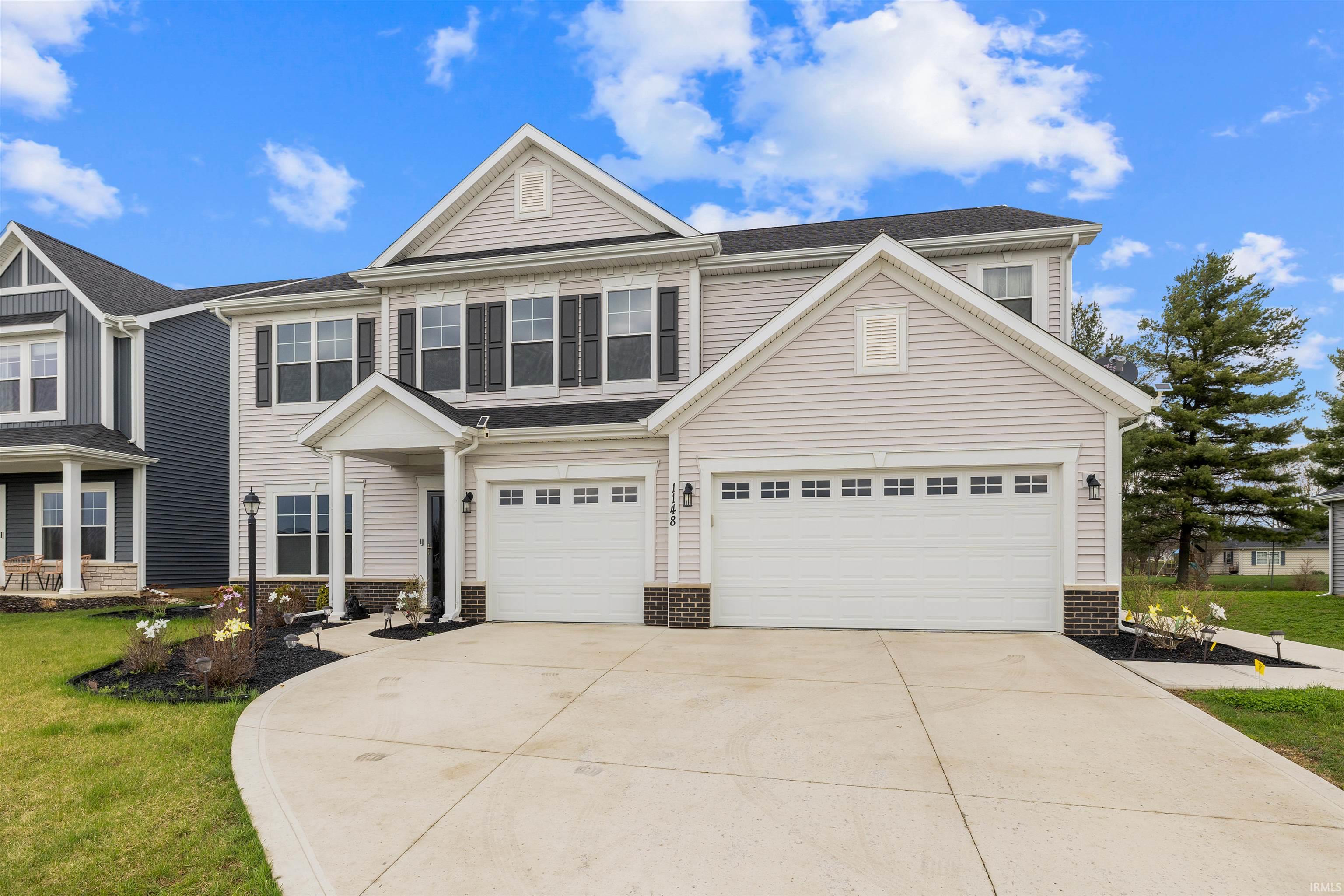 Traditional-style house featuring concrete driveway, brick siding, an attached garage, and a front lawn
