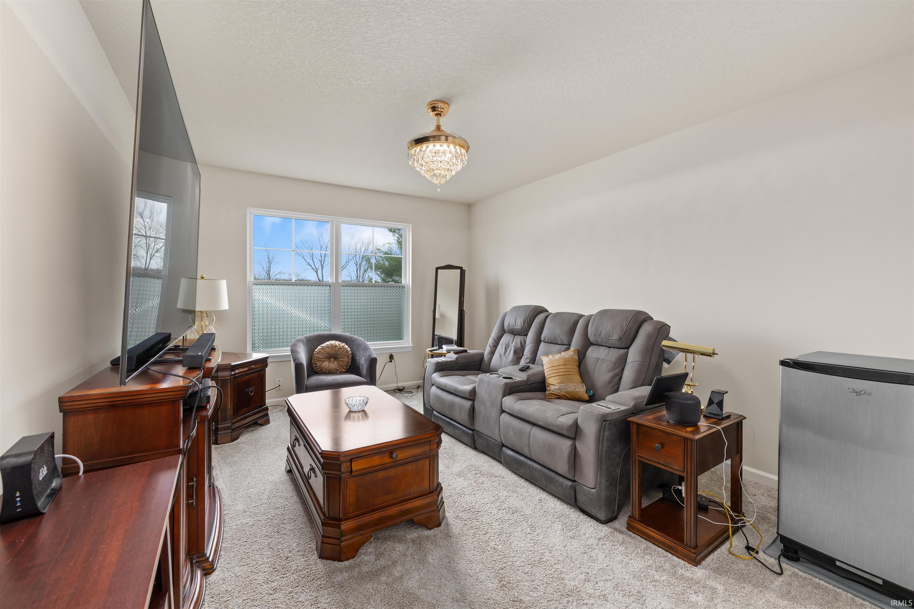 Living area featuring light colored carpet, a textured ceiling, and hanging lights