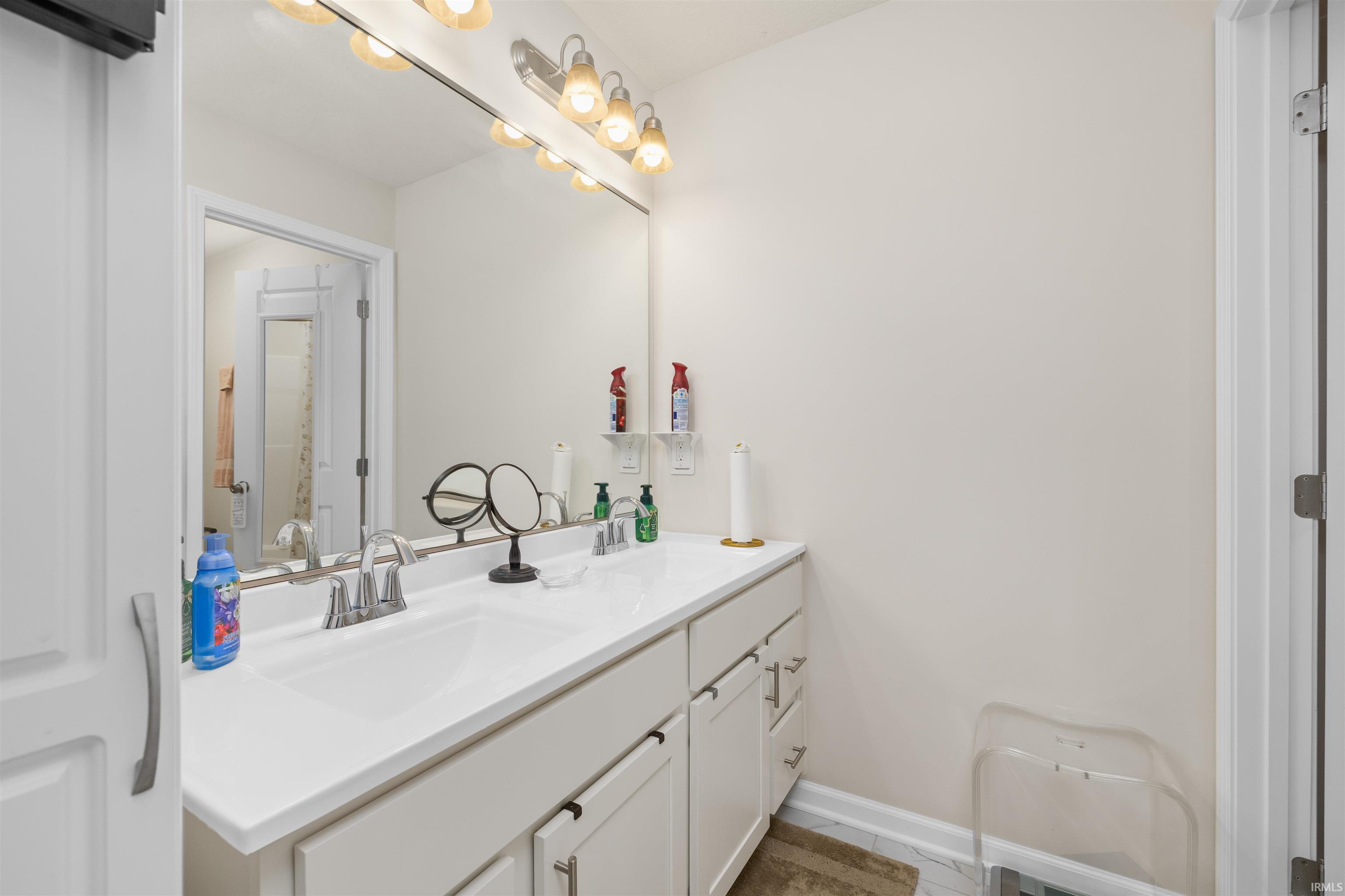 Full bath with double vanity and baseboards