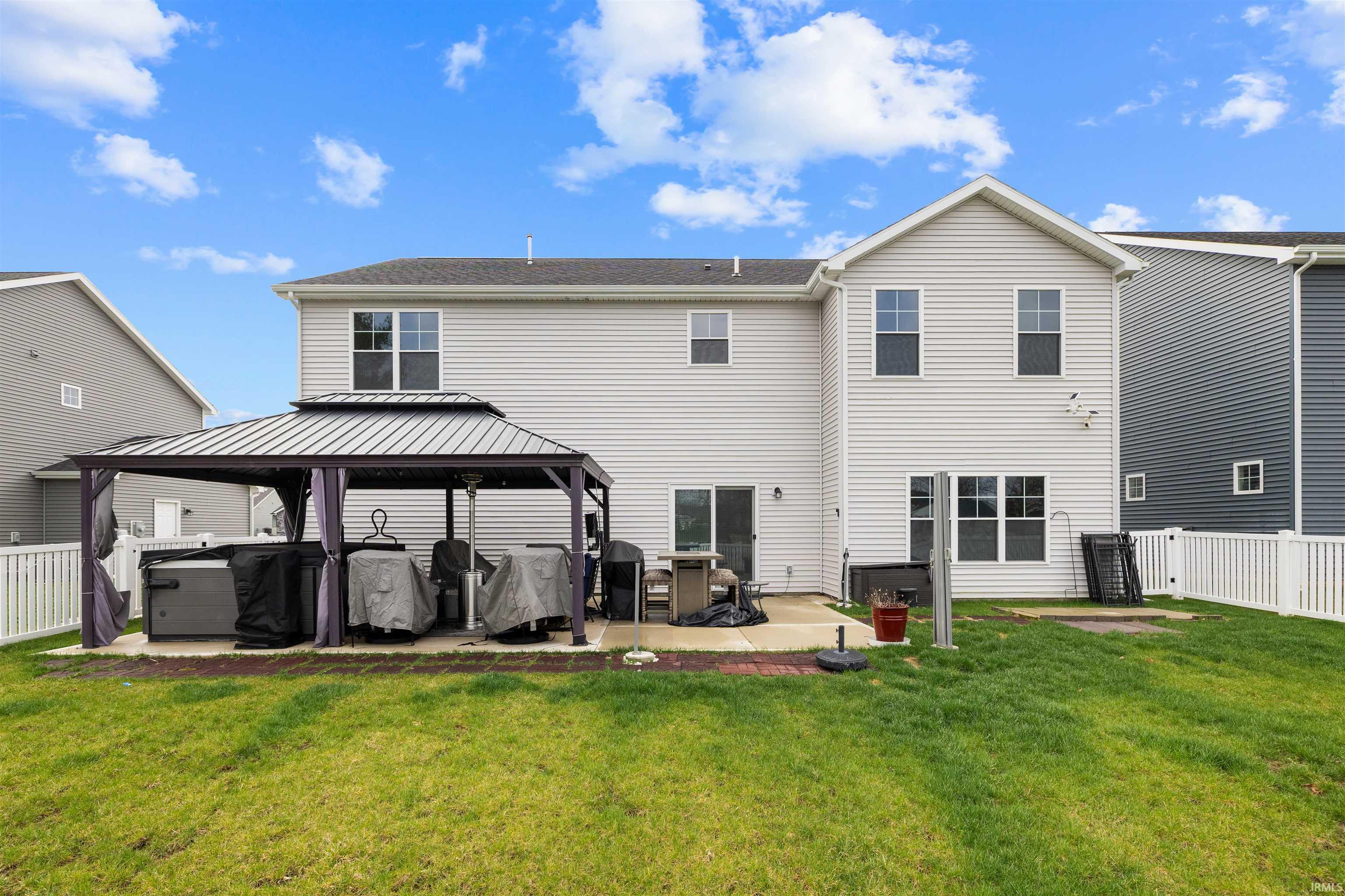 Rear view of house featuring a patio area, a gazebo, a fenced backyard, and a jacuzzi