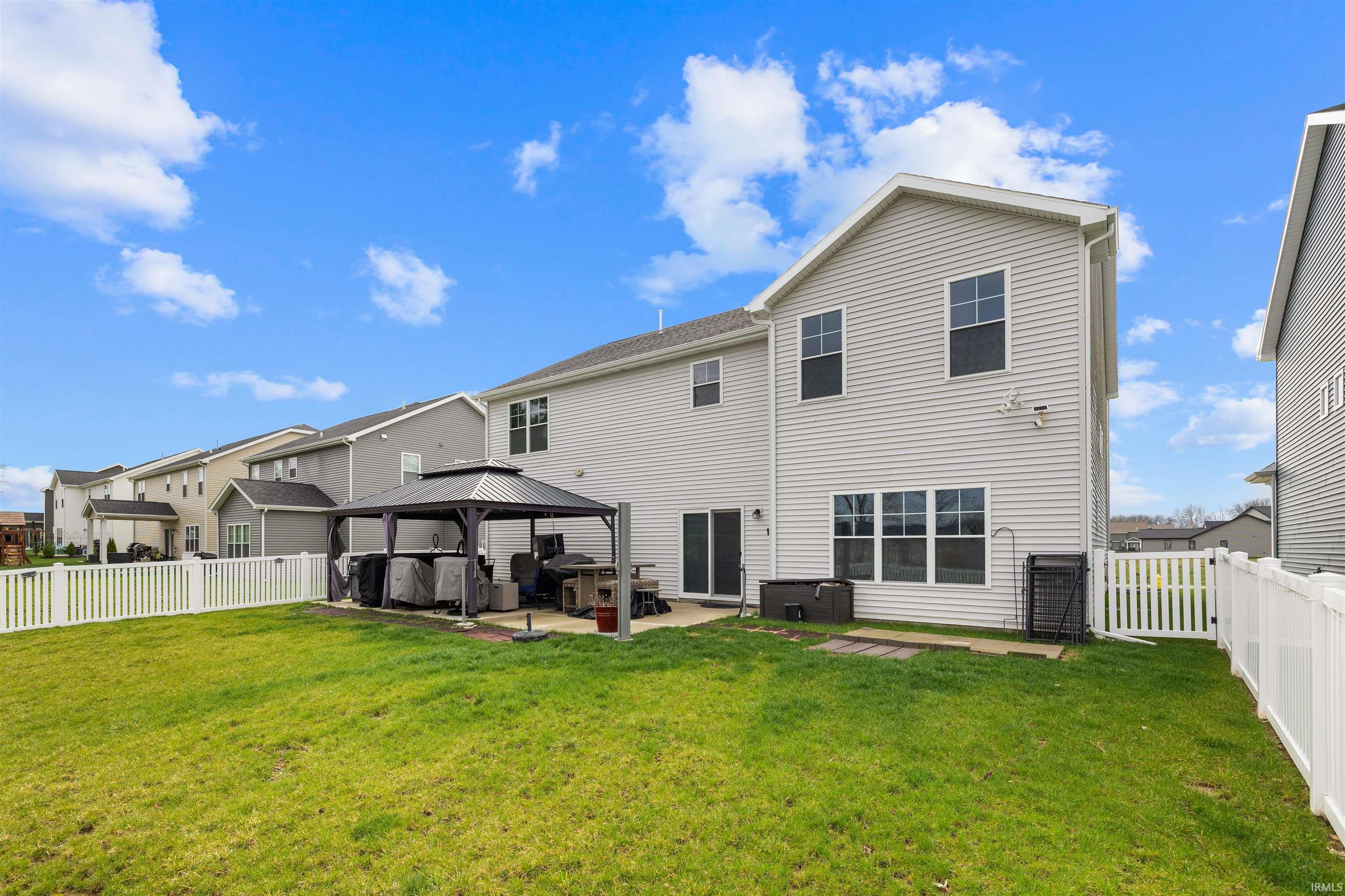 Rear view of house with a jacuzzi, a gazebo, a patio, and a fenced backyard