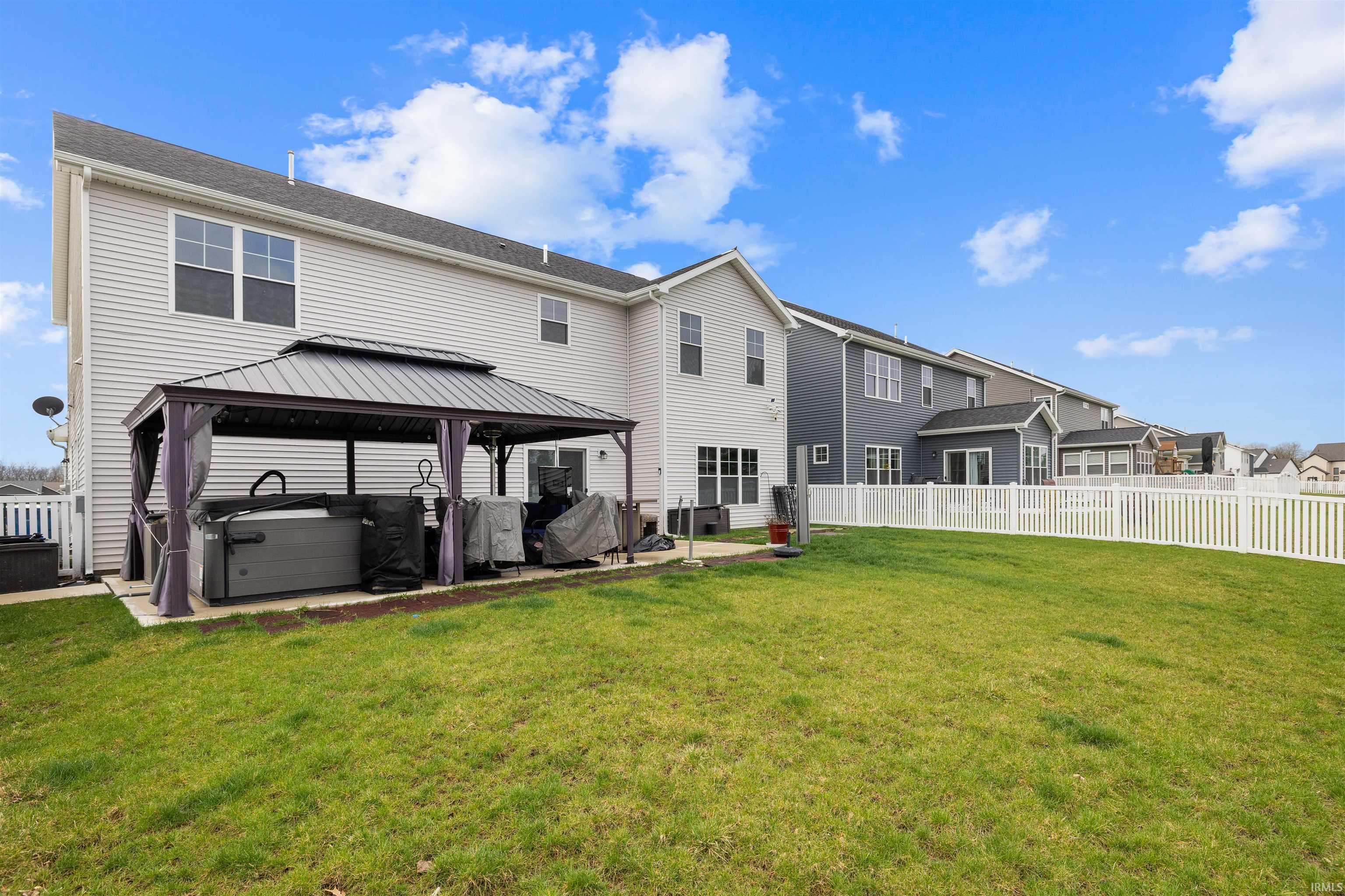 Back of property with a gazebo, a patio, a hot tub, and a residential view