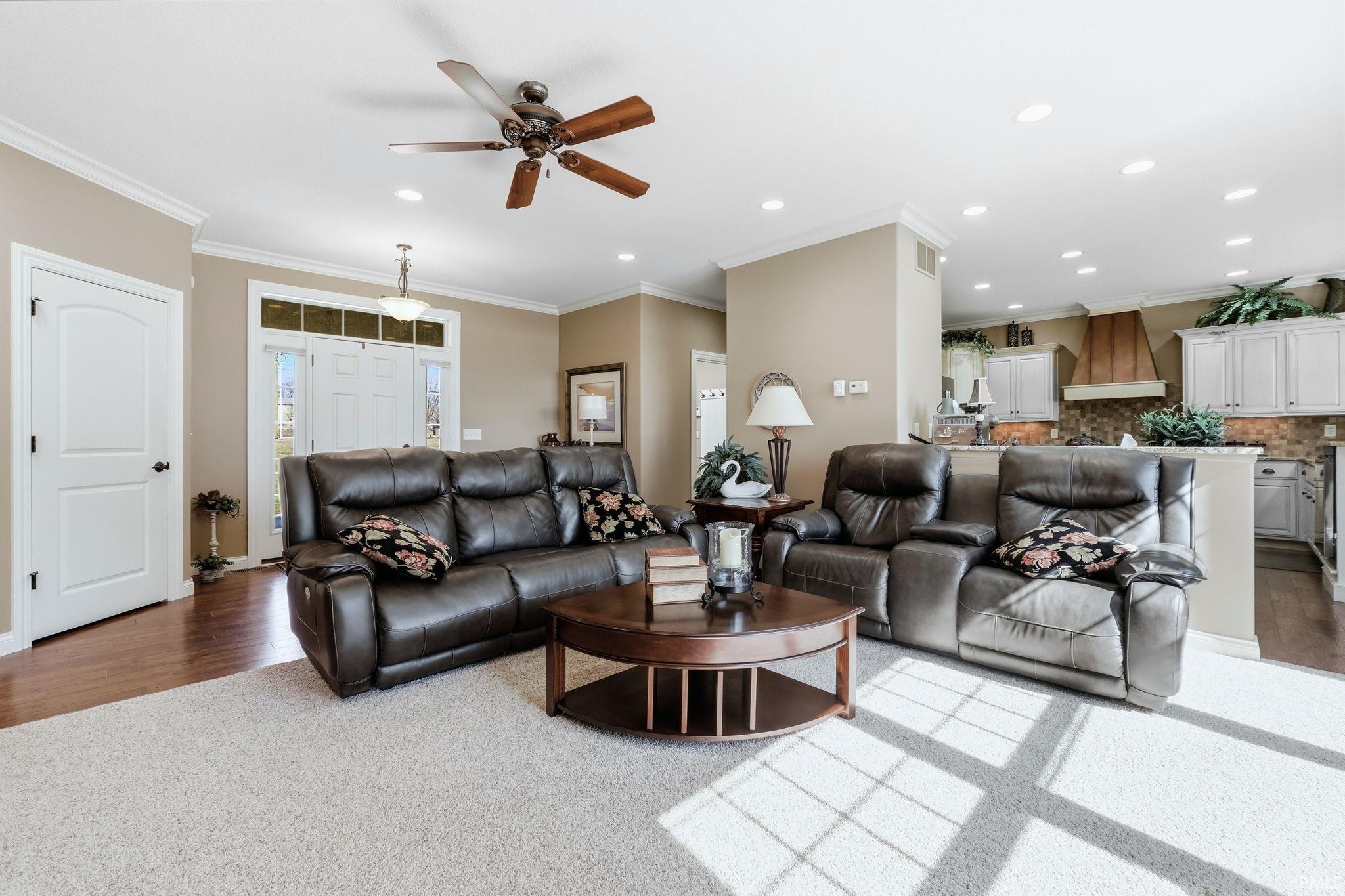 Living room featuring a ceiling fan, crown molding, recessed lighting, and light carpet