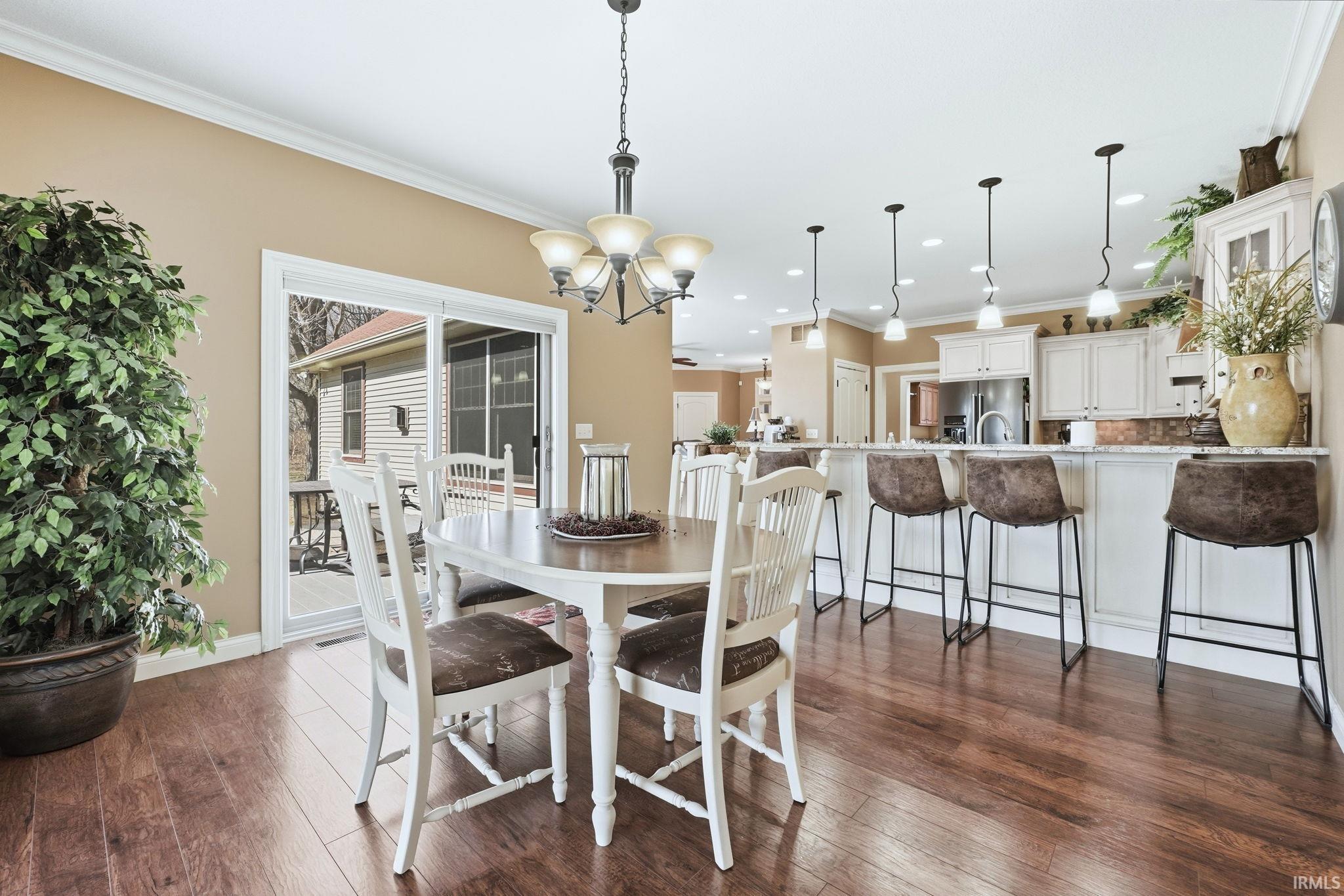 Dining space with a chandelier, dark wood-type flooring, and crown molding