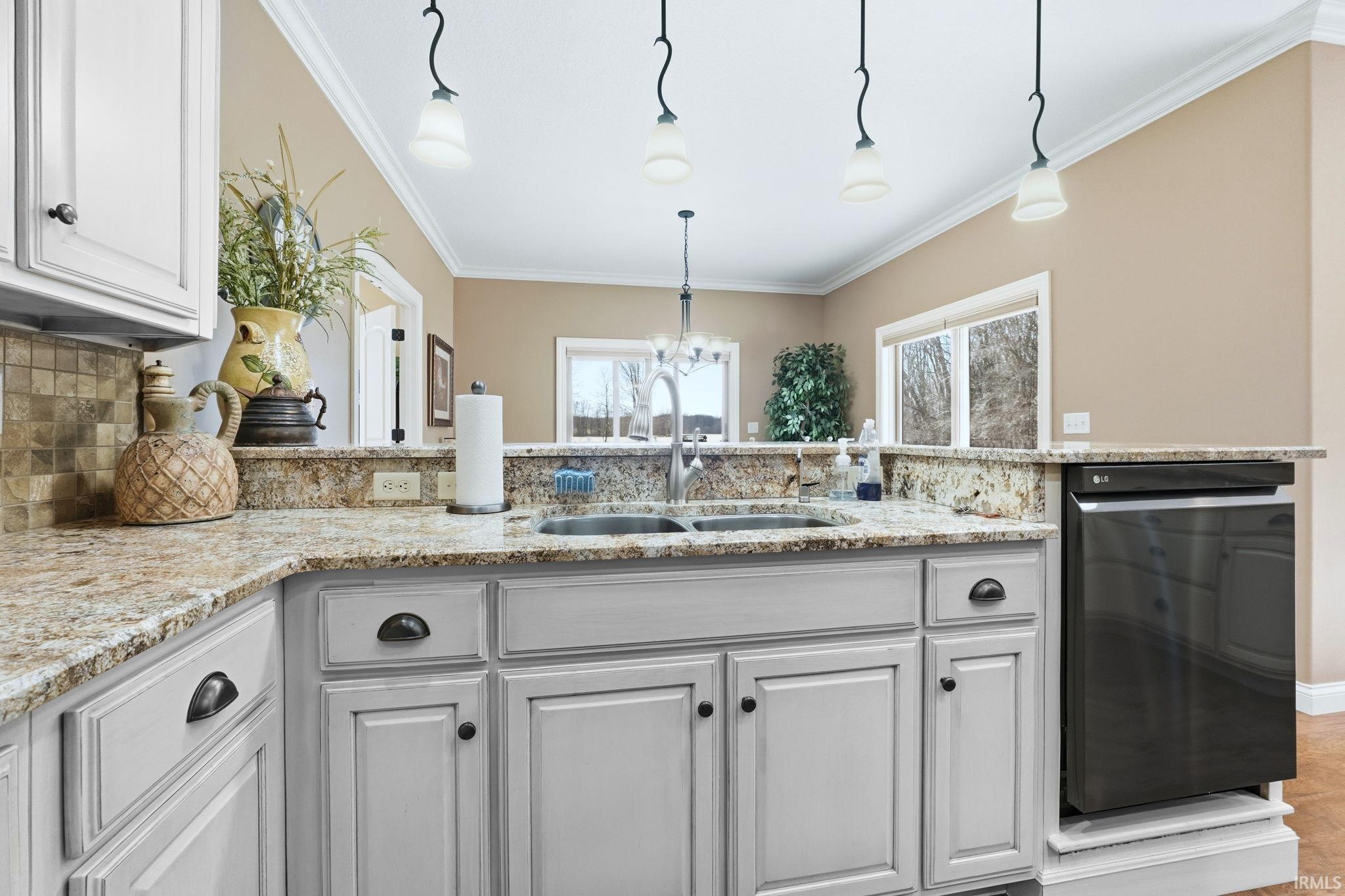 Kitchen with light stone counters, black dishwasher, ornamental molding, suspended lighting, and backsplash