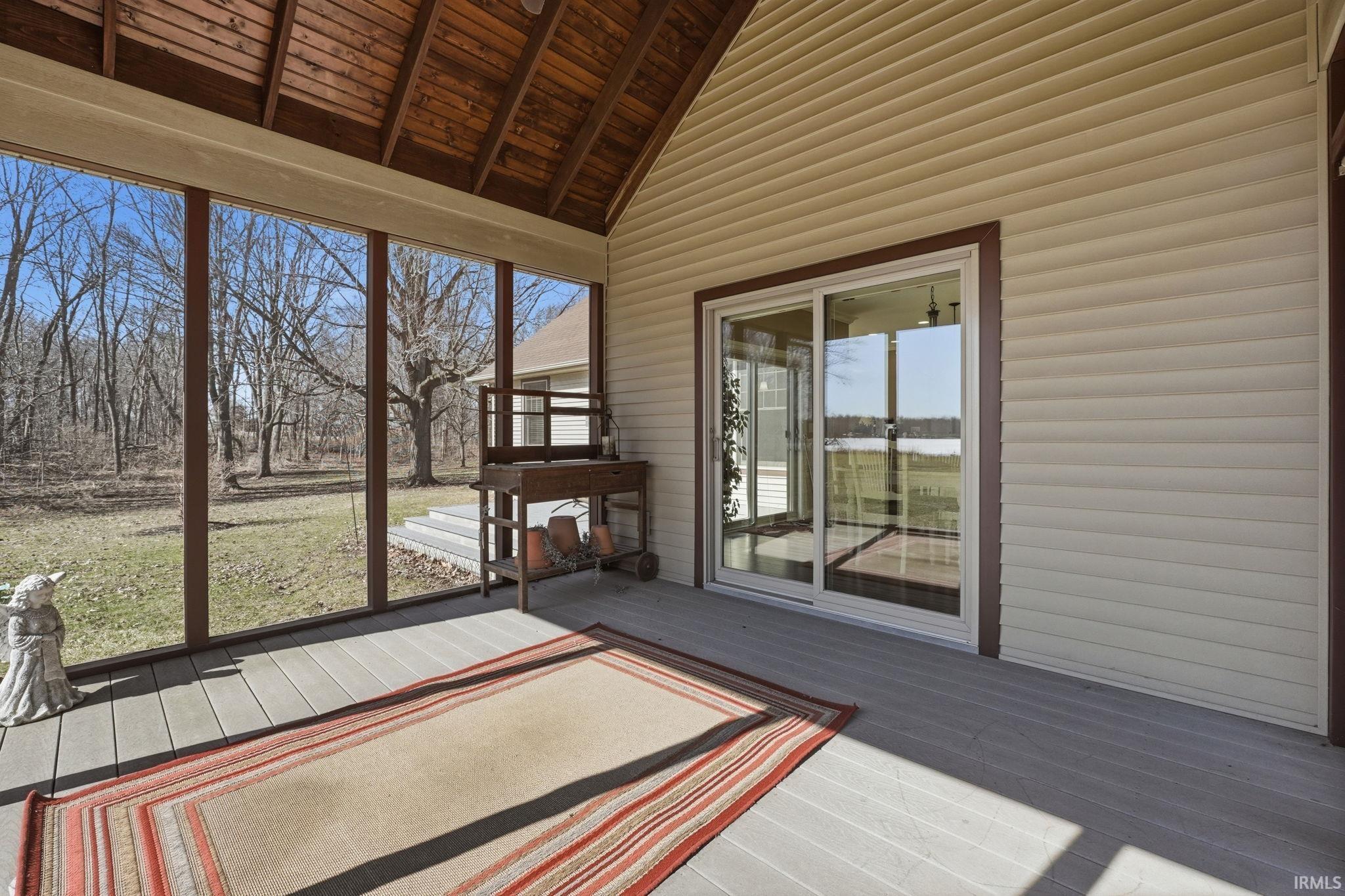 Unfurnished sunroom with vaulted ceiling and a deck