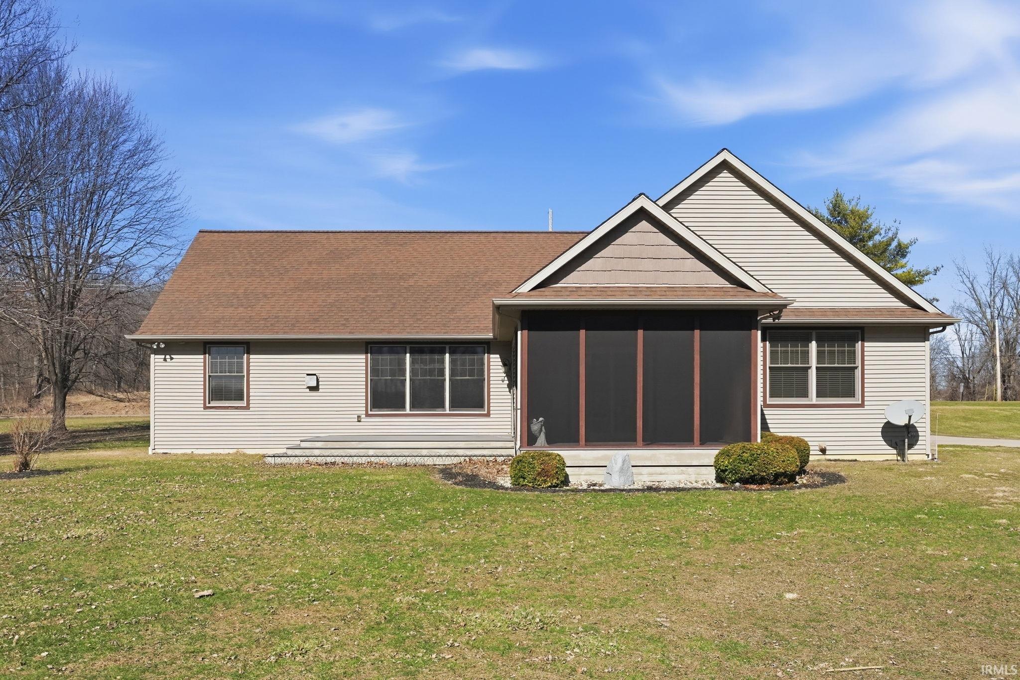 Back of house with a sunroom, a lawn, and roof with shingles