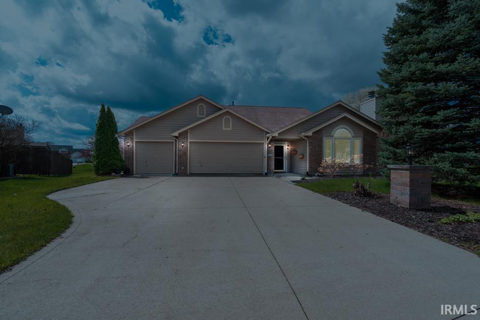 Ranch-style house featuring brick siding, an attached garage, a chimney, driveway, and a front lawn