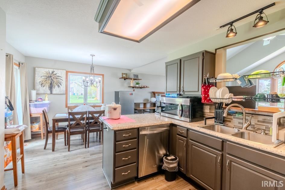 Kitchen featuring stainless steel appliances, light wood-style flooring, a peninsula, backsplash, and gray cabinets