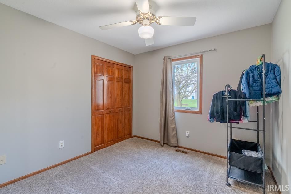 Bedroom featuring light carpet, ceiling fan, and a closet
