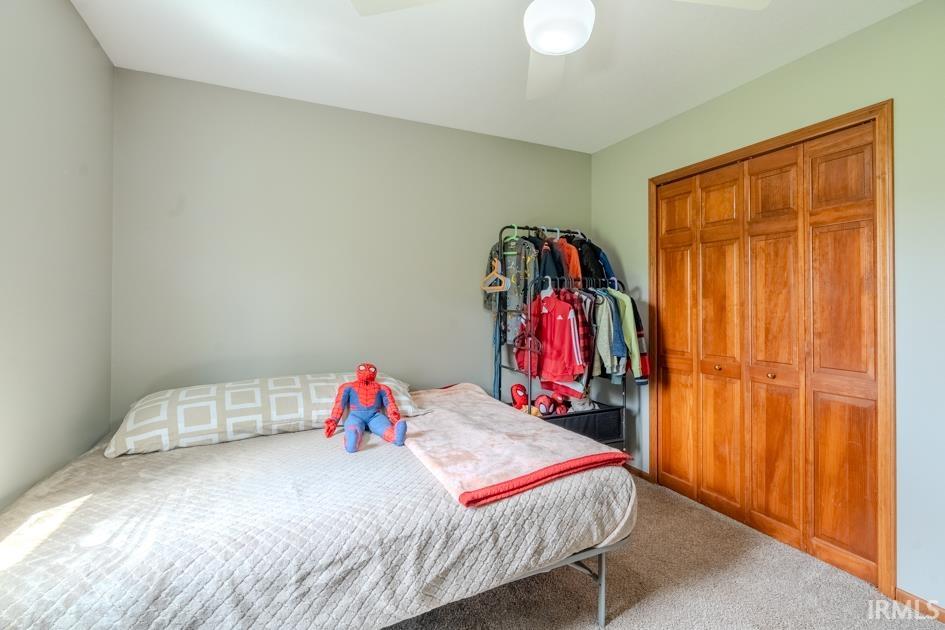 Carpeted bedroom featuring a closet and ceiling fan