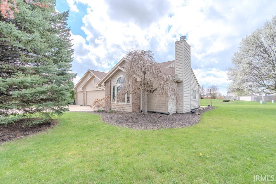 View of home's exterior with a lawn, a chimney, and a garage