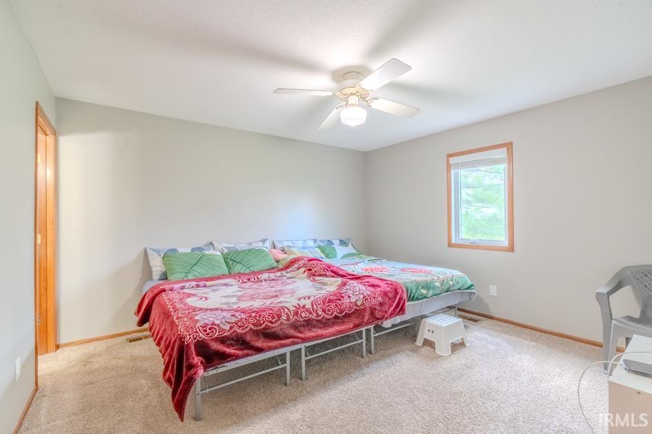 Bedroom with light colored carpet and ceiling fan